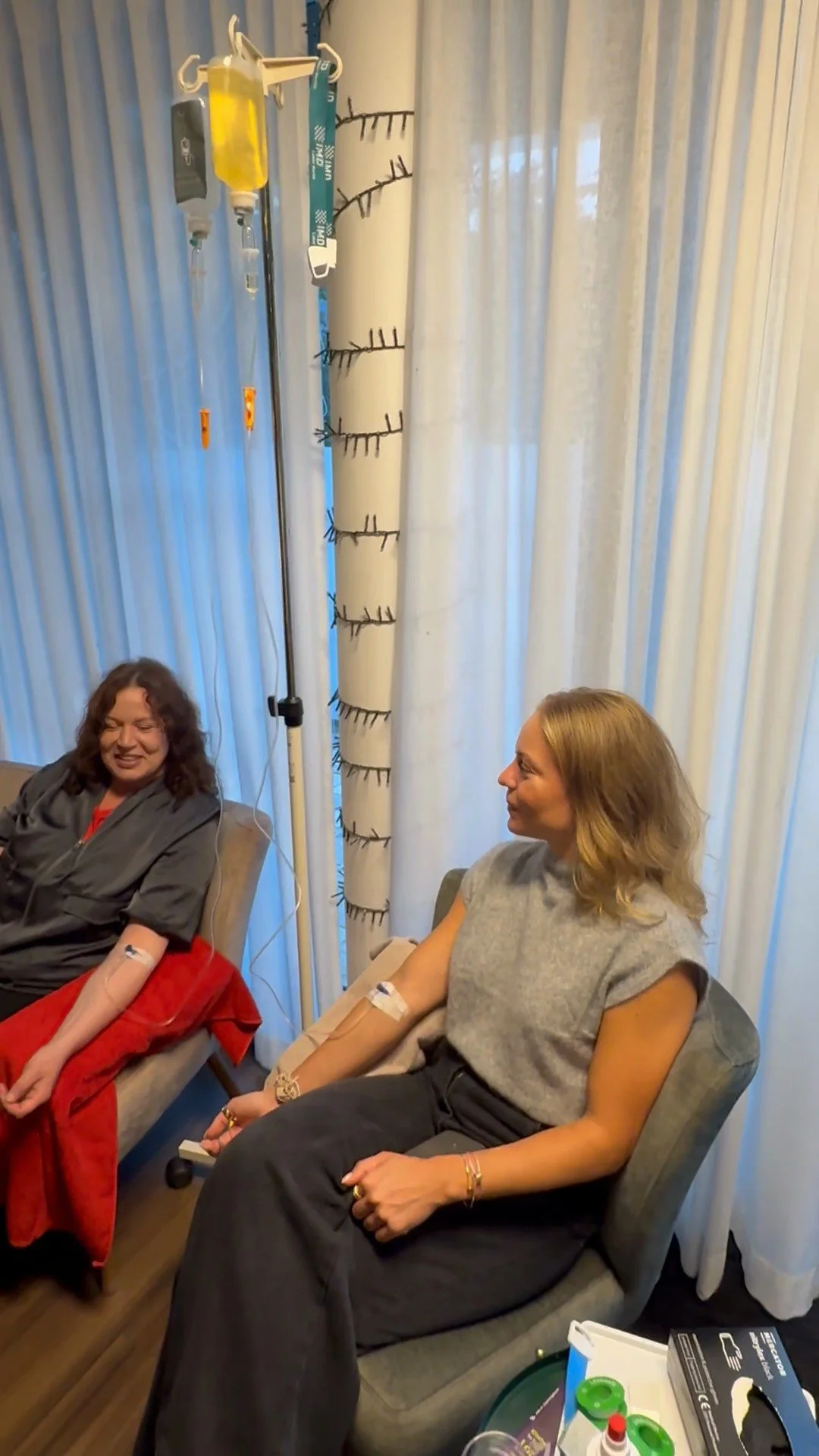 Zwei Gäste sitzen nebeneinander mit Infusion am Fenster und unterhalten sich, Longevity-Nachmittag in Rostock