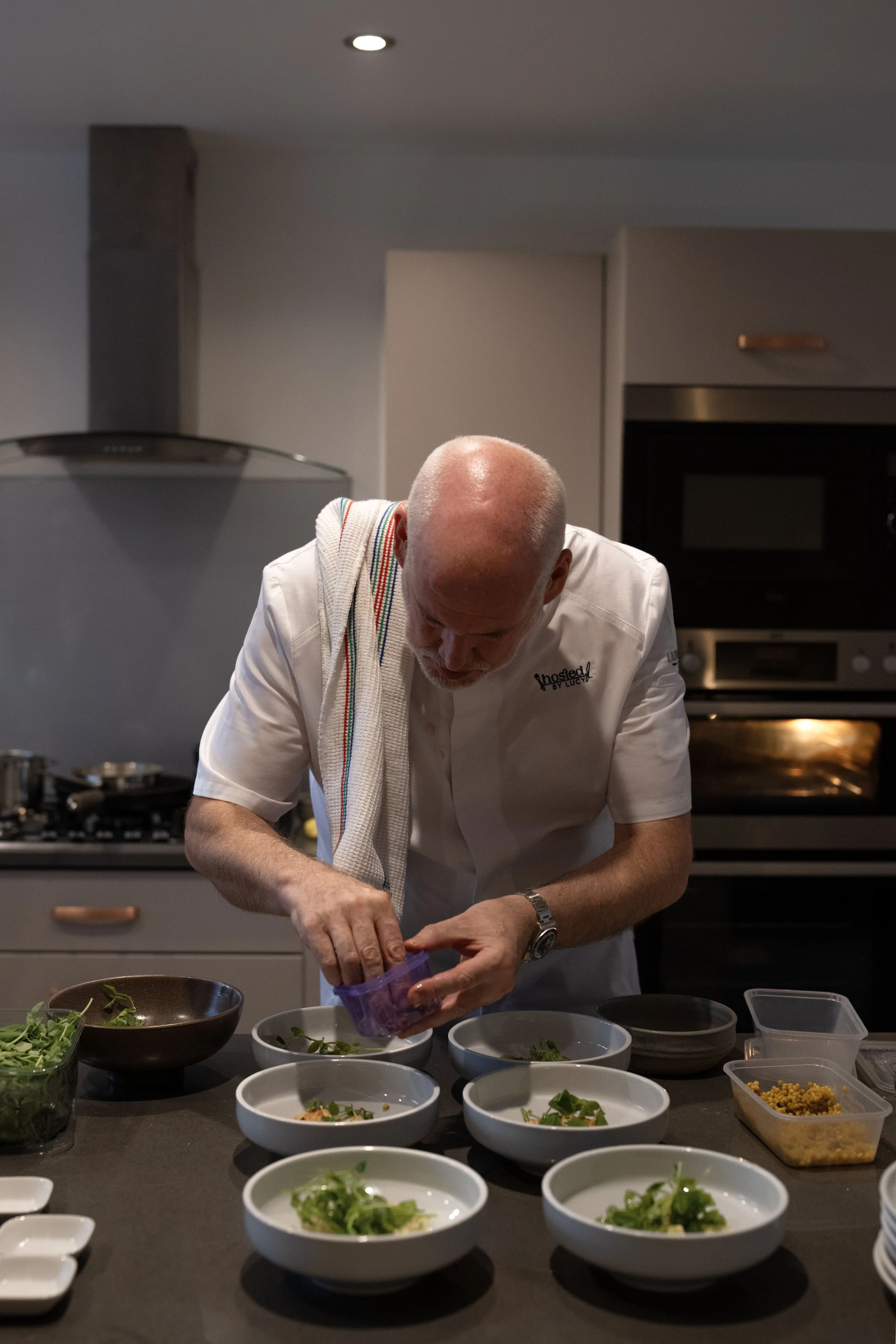 A chef garnishing dishes with greens in a modern kitchen.