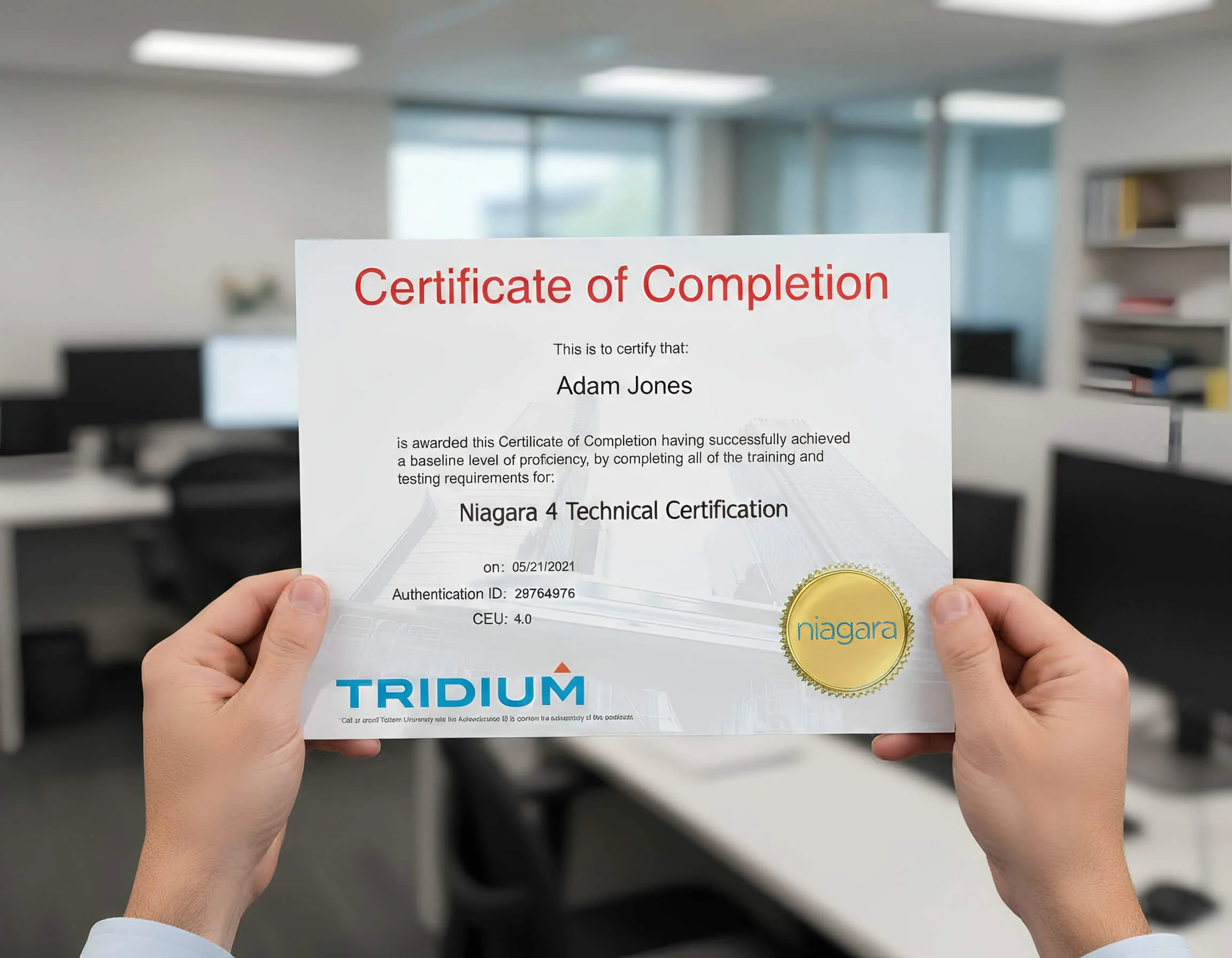 A person holding a Certificate of Completion with a gold seal, in an office environment with blurred desks and shelves in the background.