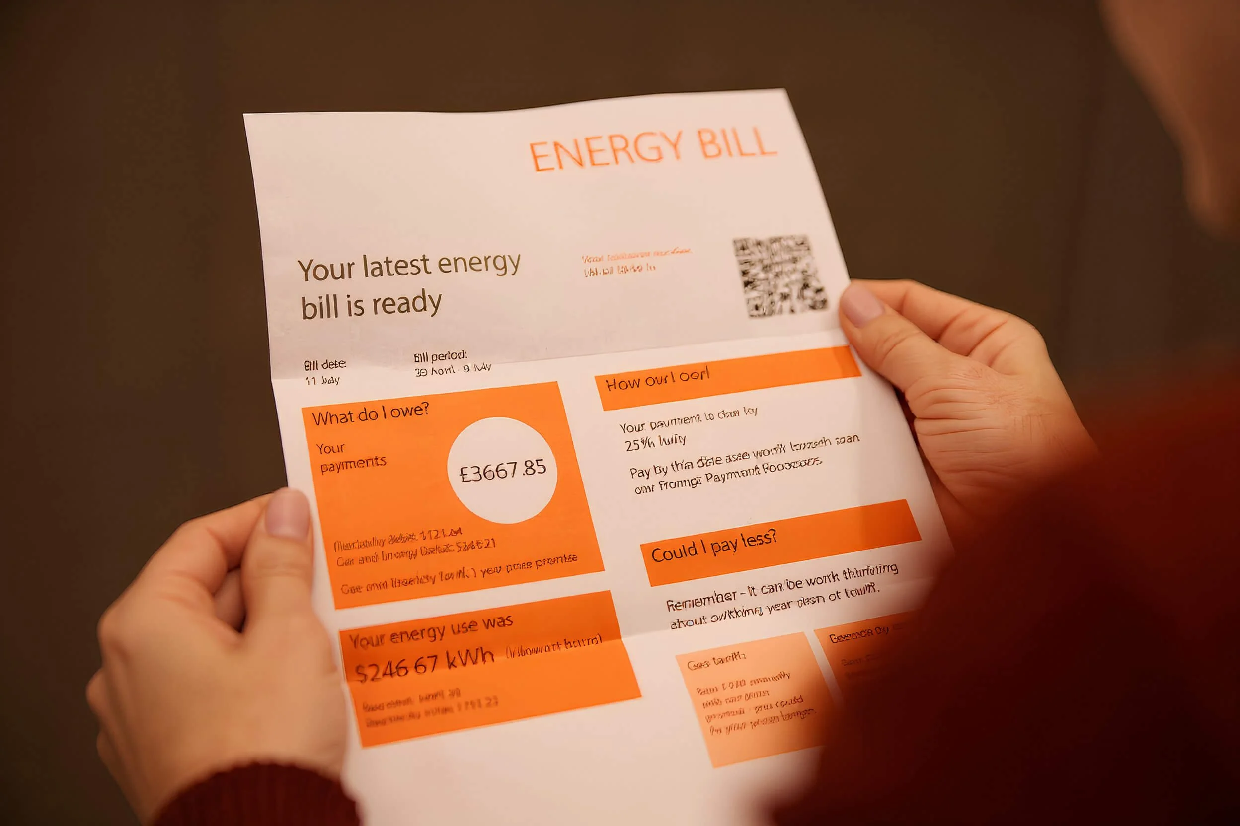 Close-up of a person holding an energy bill, which displays the amount payable as £3667.85, with sections for energy usage, payment options, and payment date, on a dark background.