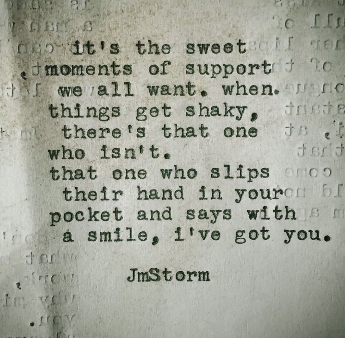 Close-up photograph of a typed motivational quote on paper, attributed to Jm Storm, about support and kindness. The text is slightly blurry and the paper shows some shadow and texture.