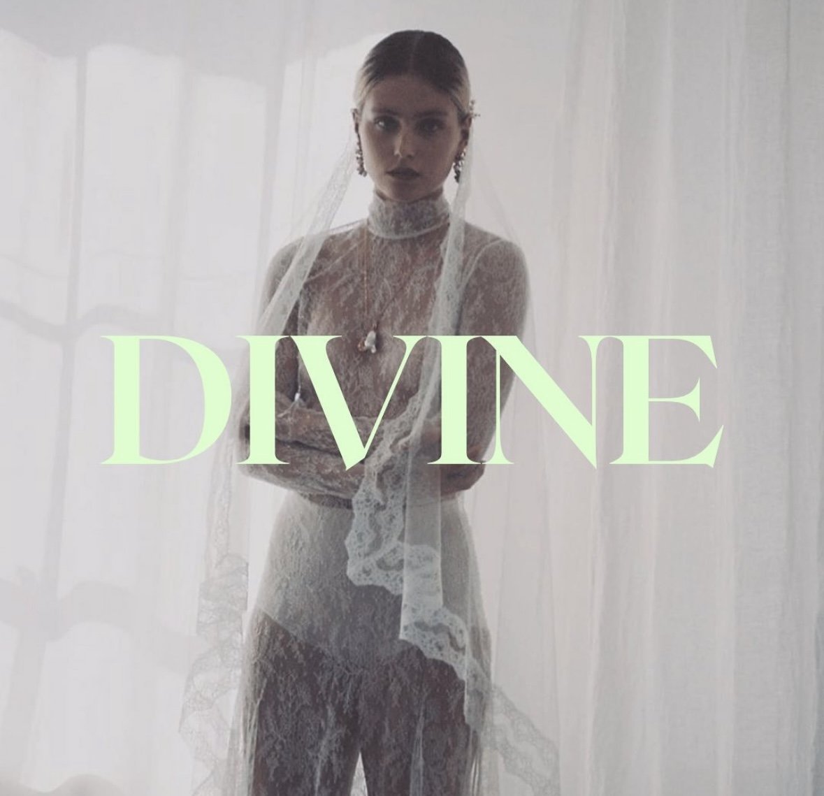 Woman dressed in a lace bridal gown with a veil, looking at the camera, with the word "DIVINE" written across her. The background features sheer curtains.