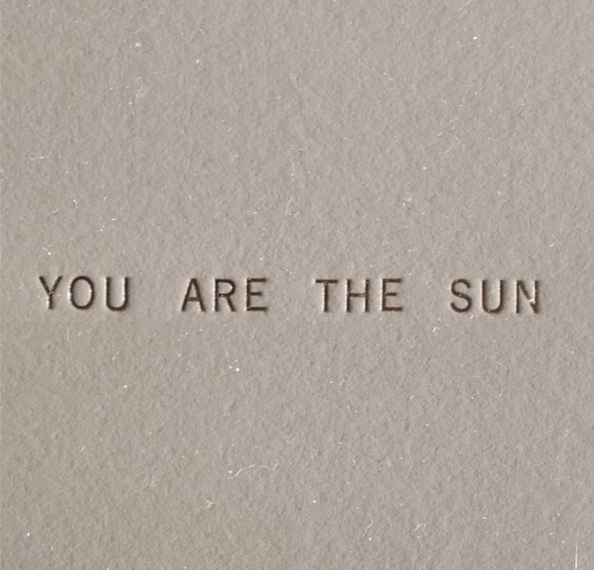 Embossed text on a beige surface that reads, 'You are the sun.'