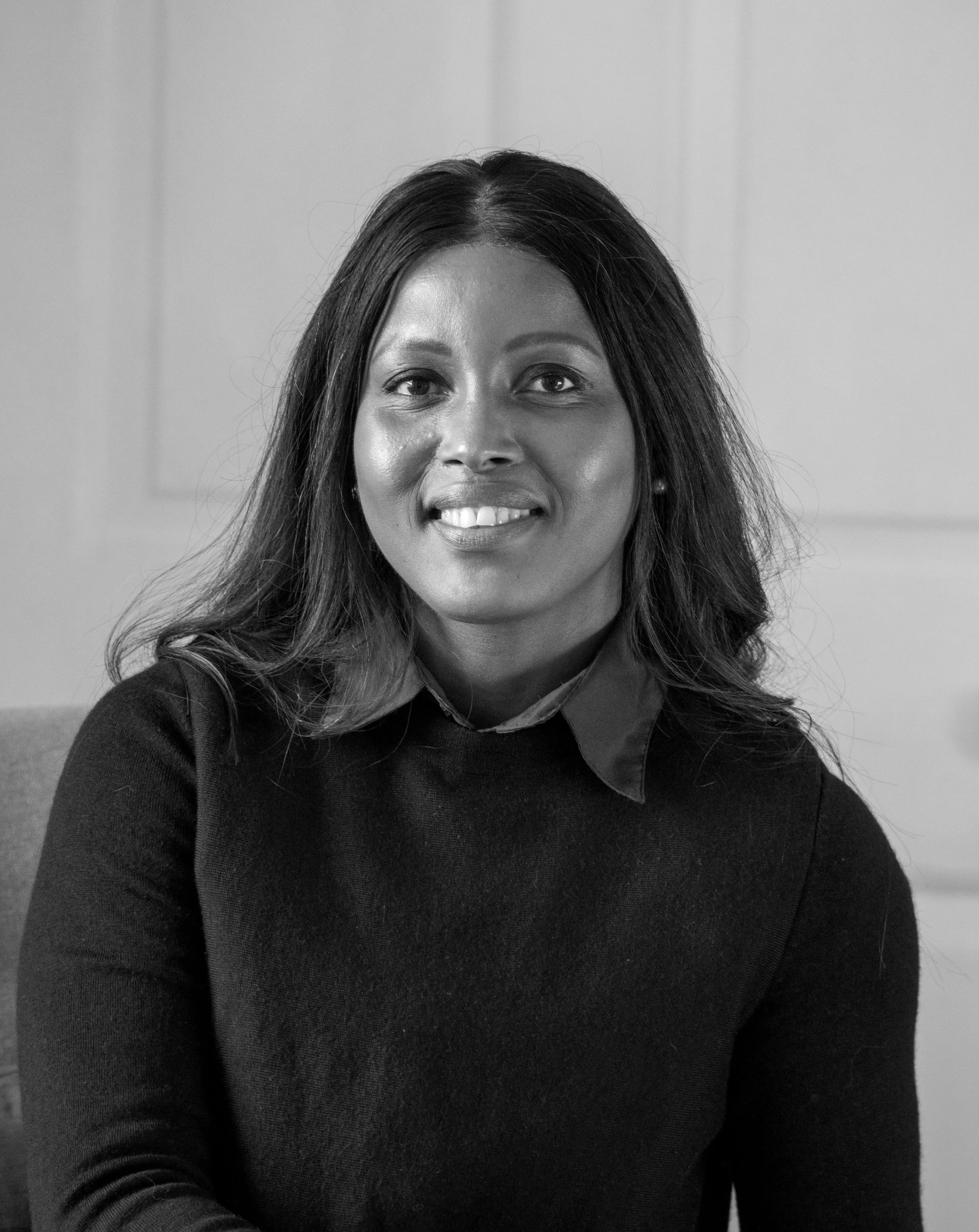 Portrait of an African American woman with long dark hair, smiling, in black and white.