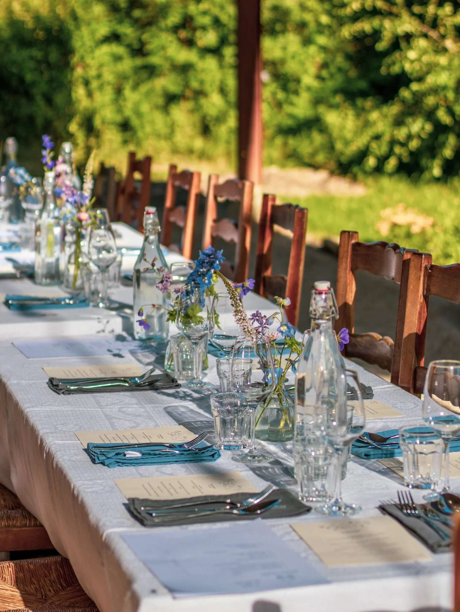 Table de repas d'extérieur avec des compositions florales au centre.