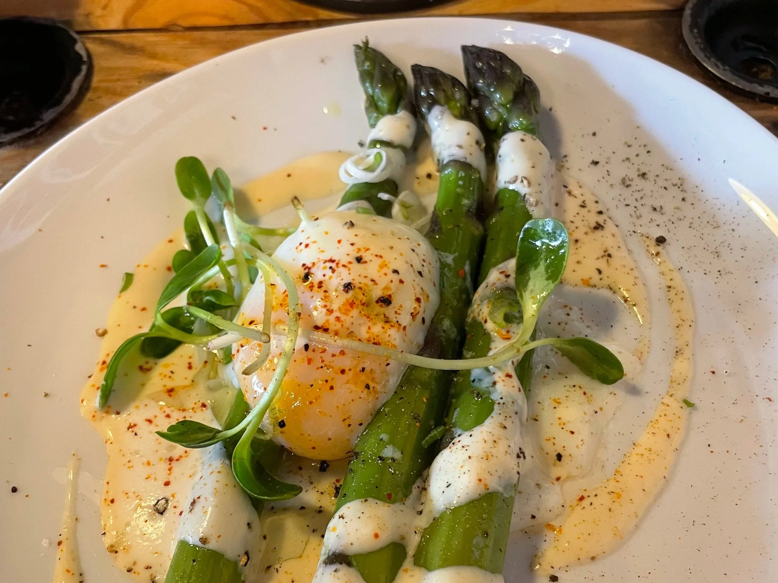 Poached eggs with seasoning and greens on a white plate.