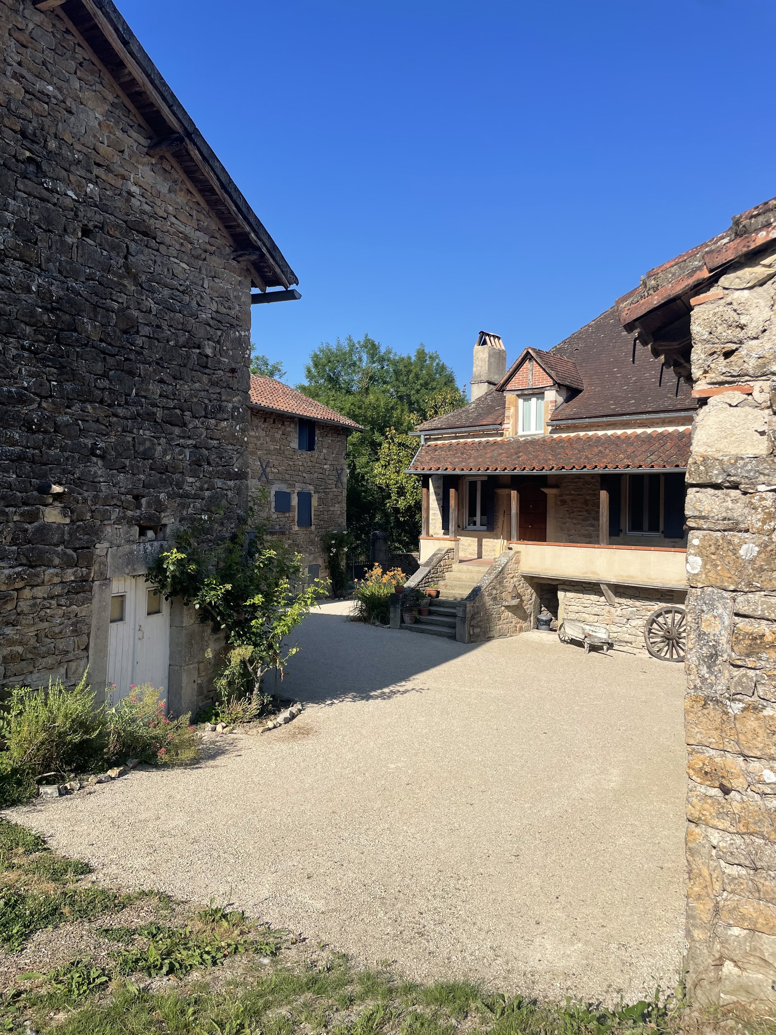 Rustic stone buildings with greenery and a clear blue sky.