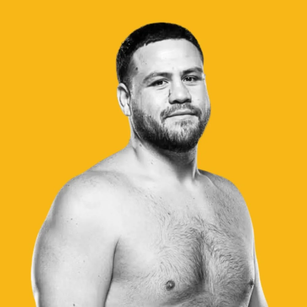 Black and white photo of a shirtless man with a beard against a yellow background.