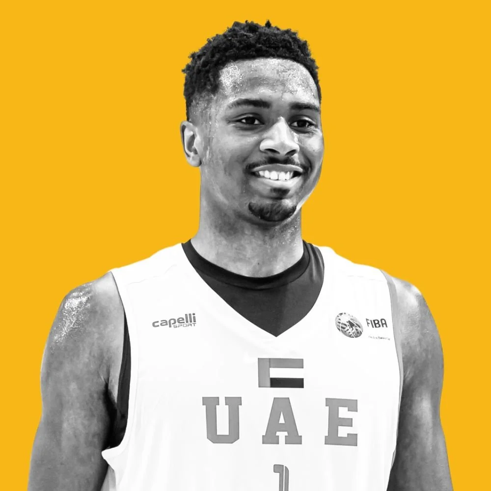 A smiling basketball player wearing a UAE national team jersey against a yellow background.