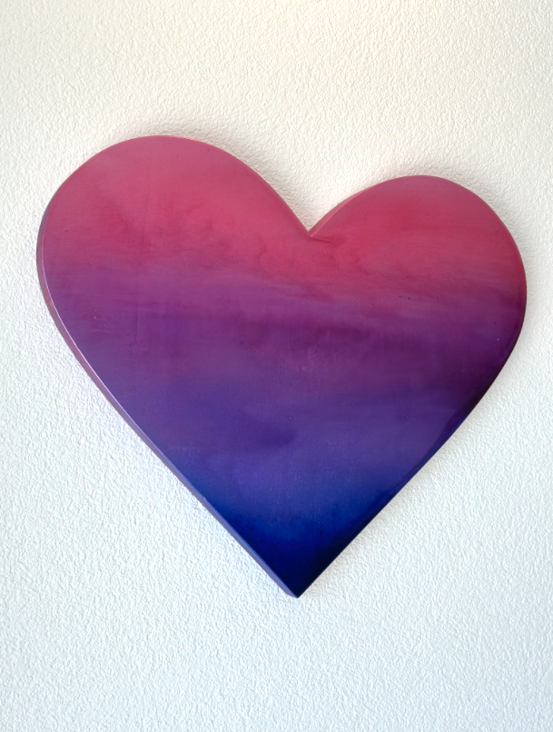 Kunstwerk in Herzform mit Farbverlauf von Pink zu Blau, an einer weißen Wand von der Künstlerin Valentina Blumer