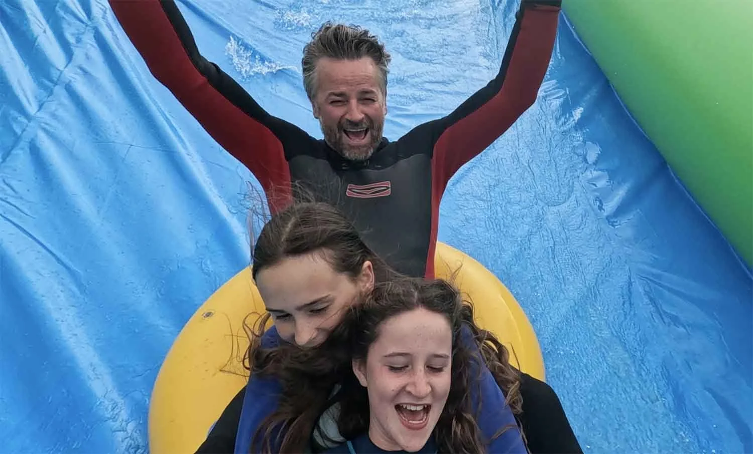 Dad and teenagers enjoy the giant slip and slide near winnard perch