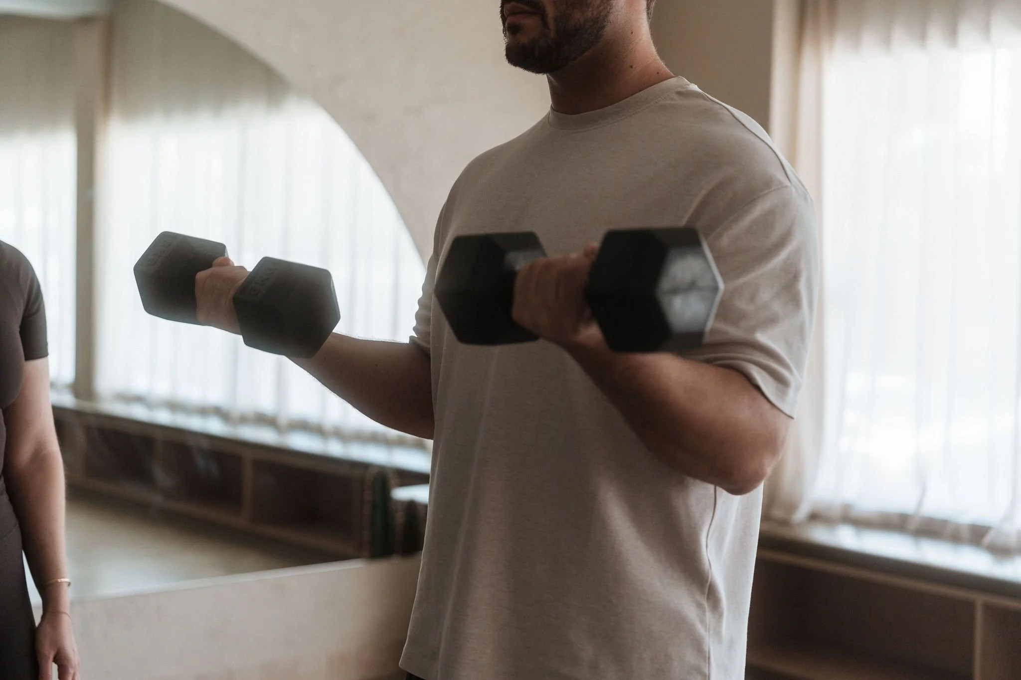 Client lifting light weights as part of a guided strength program during bypass surgery recovery at CardioCare Clinic, Bondi Junction