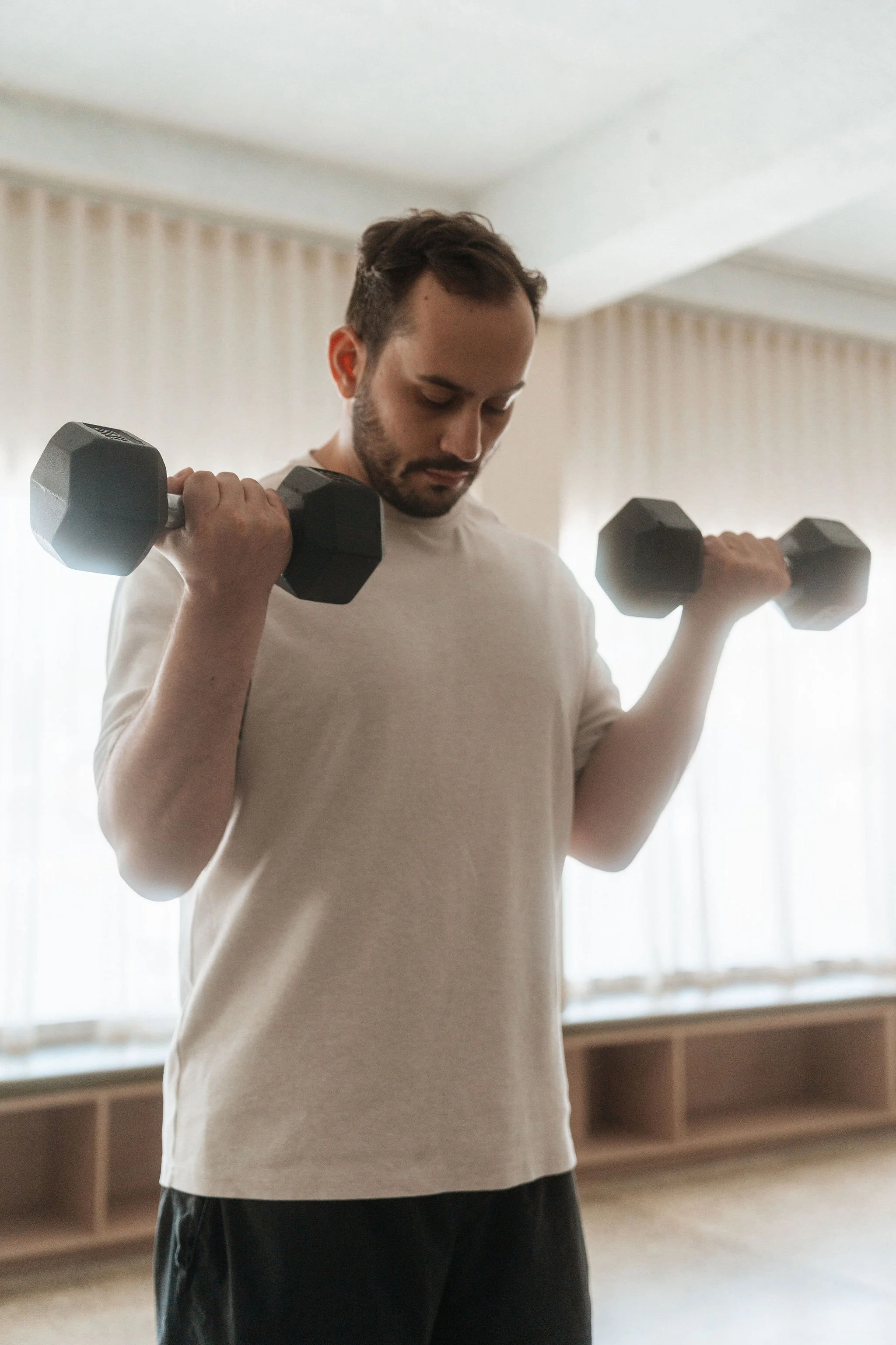 Client performing a dumbbell exercise during a 1:1 exercise physiology session at CardioCare Clinic, Bondi Junction