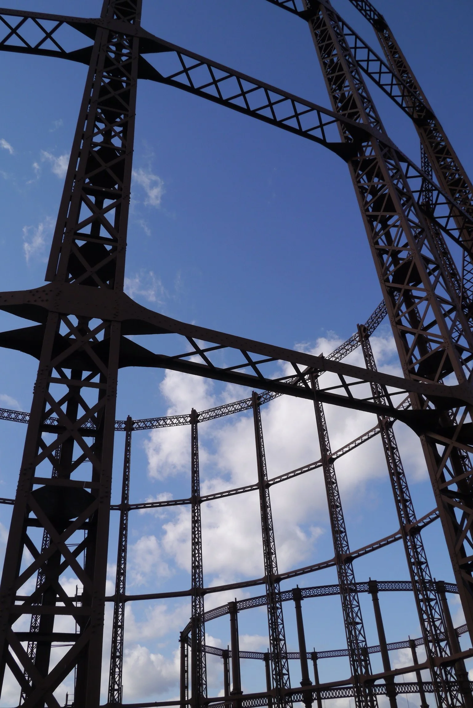 Looking up at a large steel gas tower structure against a blue sky with some clouds.