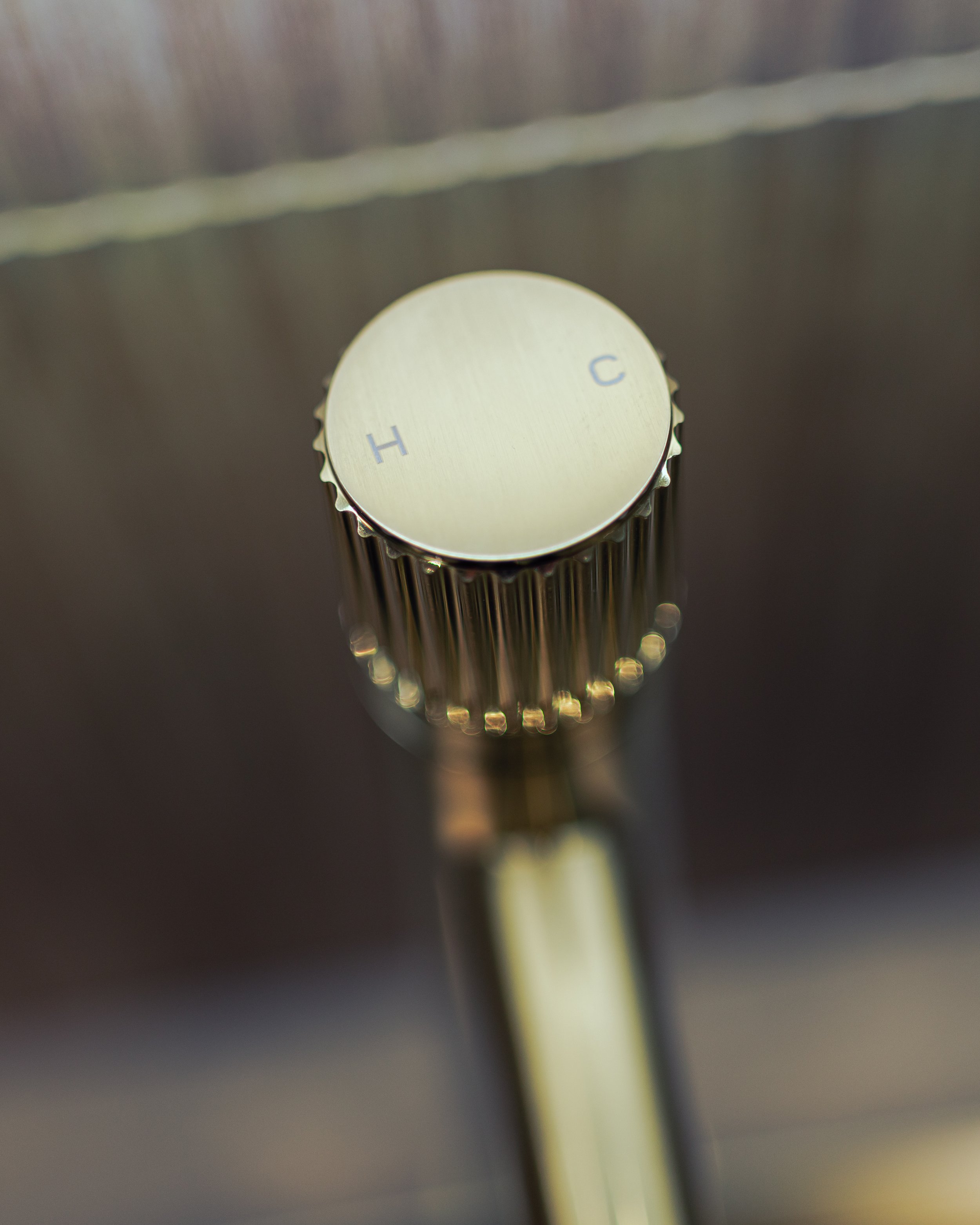 Bathroom with terrazzo tiles, white toilet, green vanity with sink, oval mirror, and a silver towel warmer with a towel hanging on it.