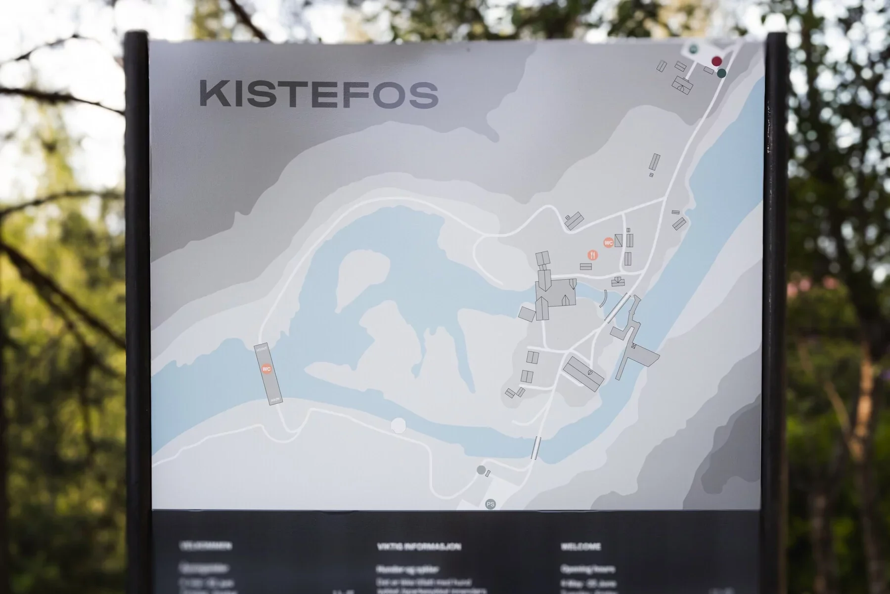 Informasjonsskilt for Kistefos, med kart over området, inkludert vann, bygninger, toaletter og andre fasiliteter. Skiltet er laget av Focus Print