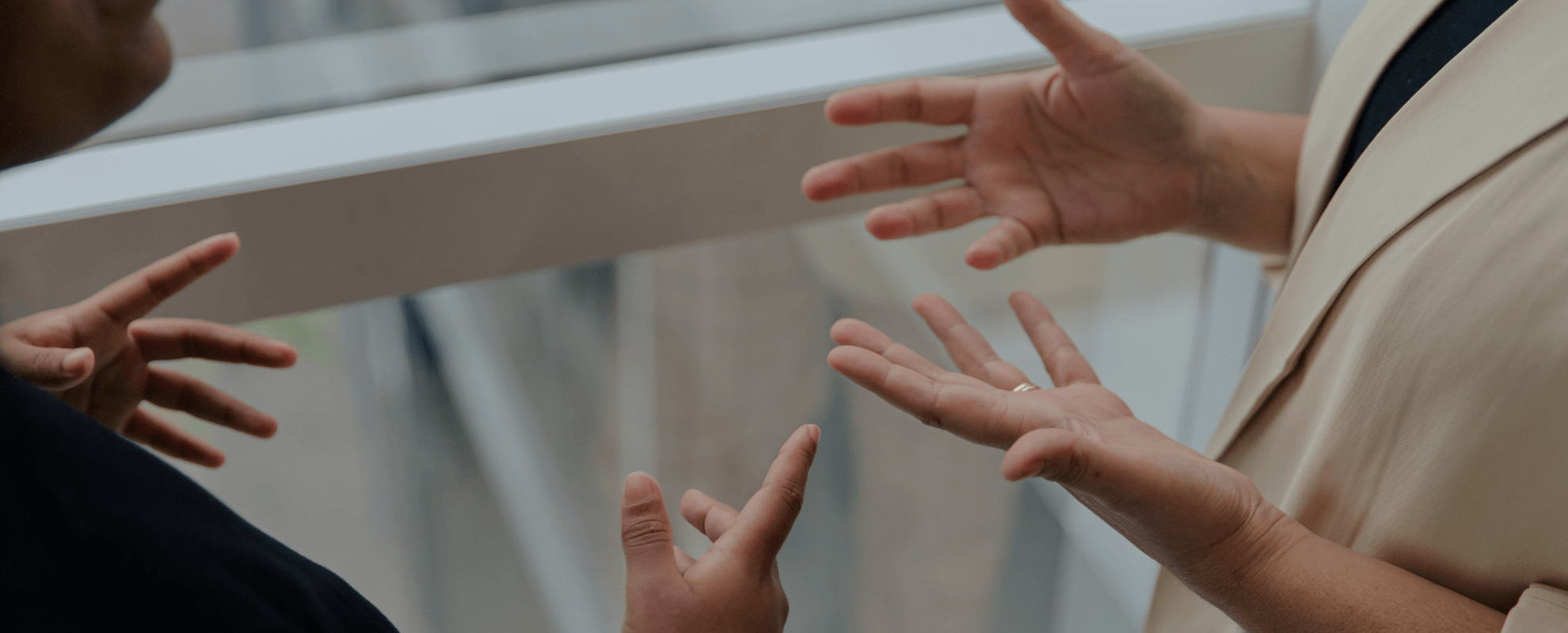 Deux personnes discutent, gesticulant avec leurs mains lors d'une conversation.