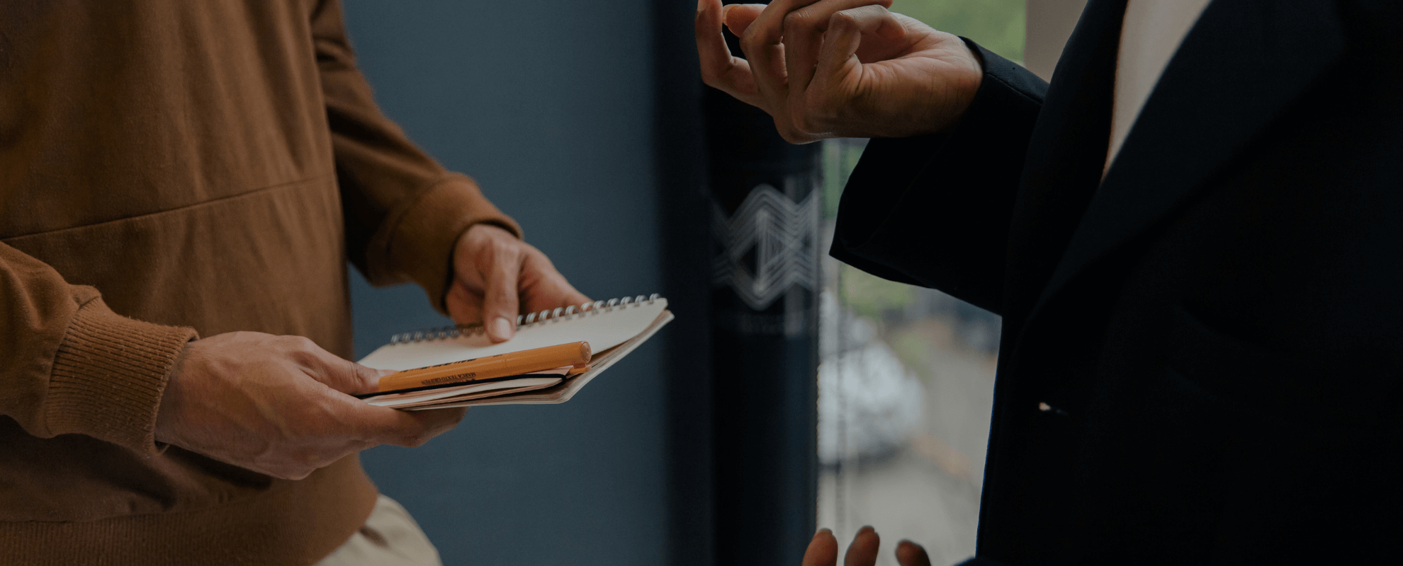 Un homme tient un cahier entre ses mains et tient une discussion avec une personne en face de lui