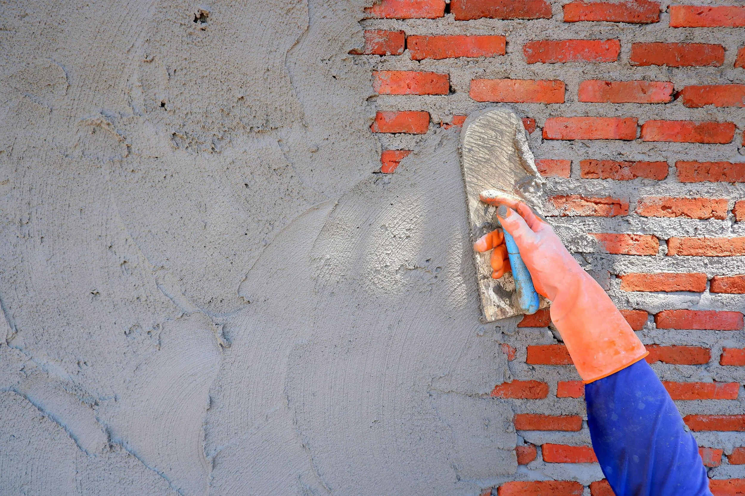 Andrew Plastering rendering brick wall with cement for smooth exterior finish.