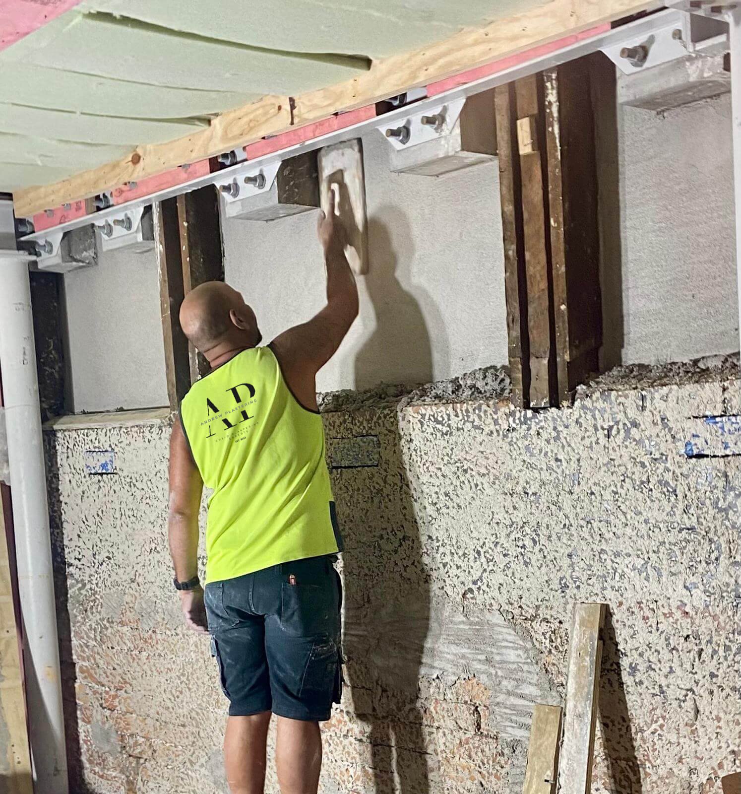 Andrew Plastering specialist repairing damaged wall during remedial plastering project.