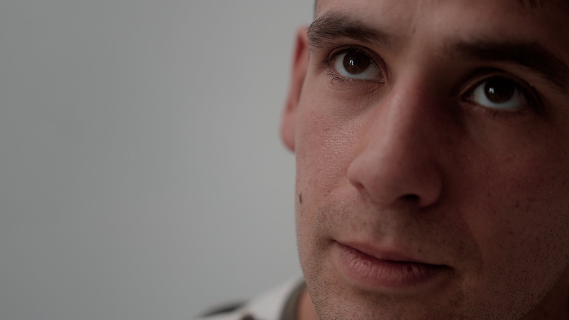 Closeup of a man against a white wall.