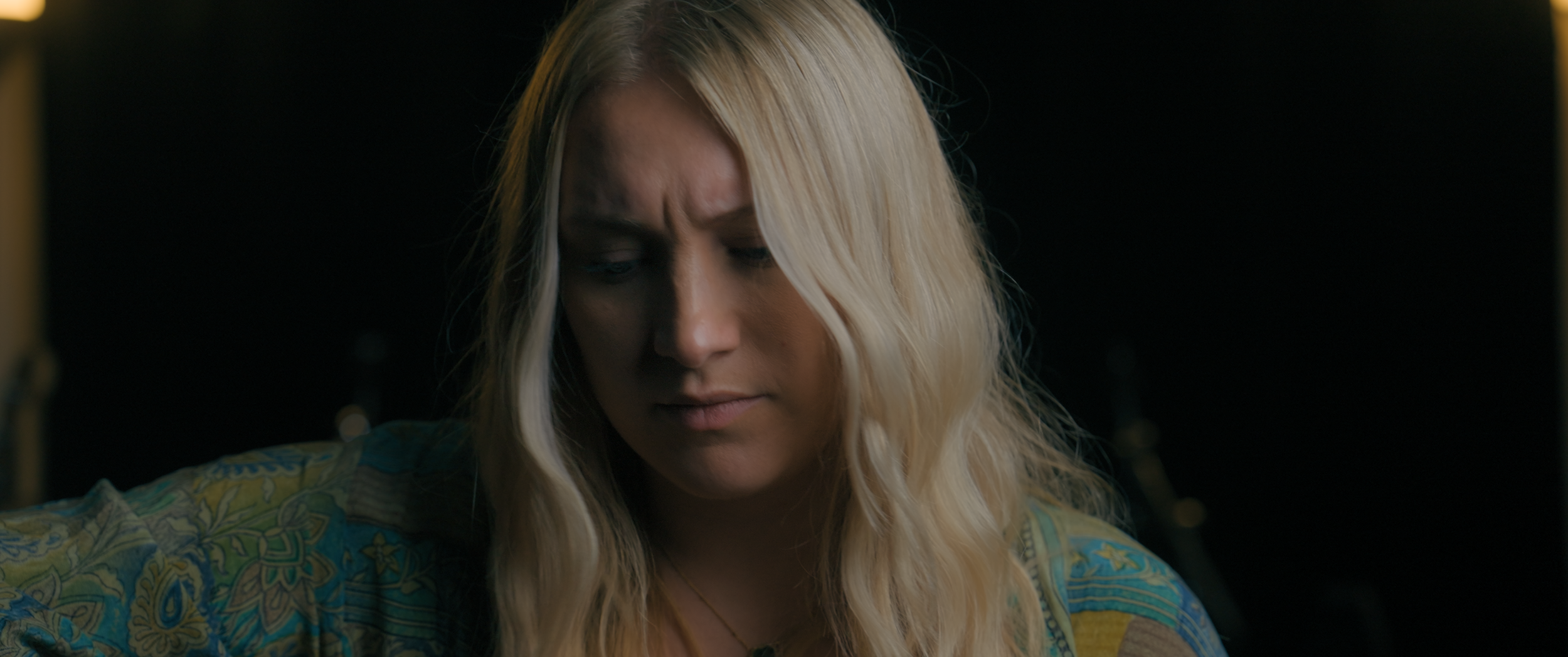 A closeup shot of a woman sat in darkness.