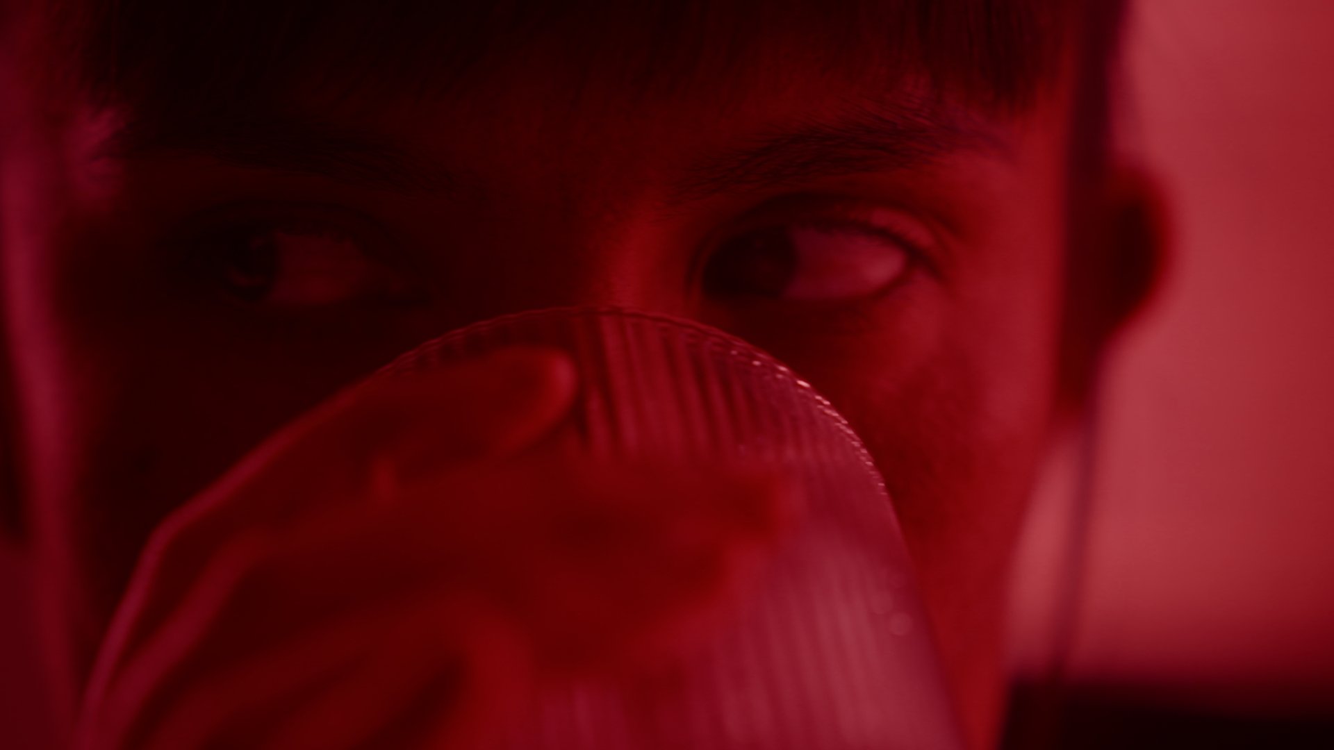Extreme closeup on a woman drinking in red light.