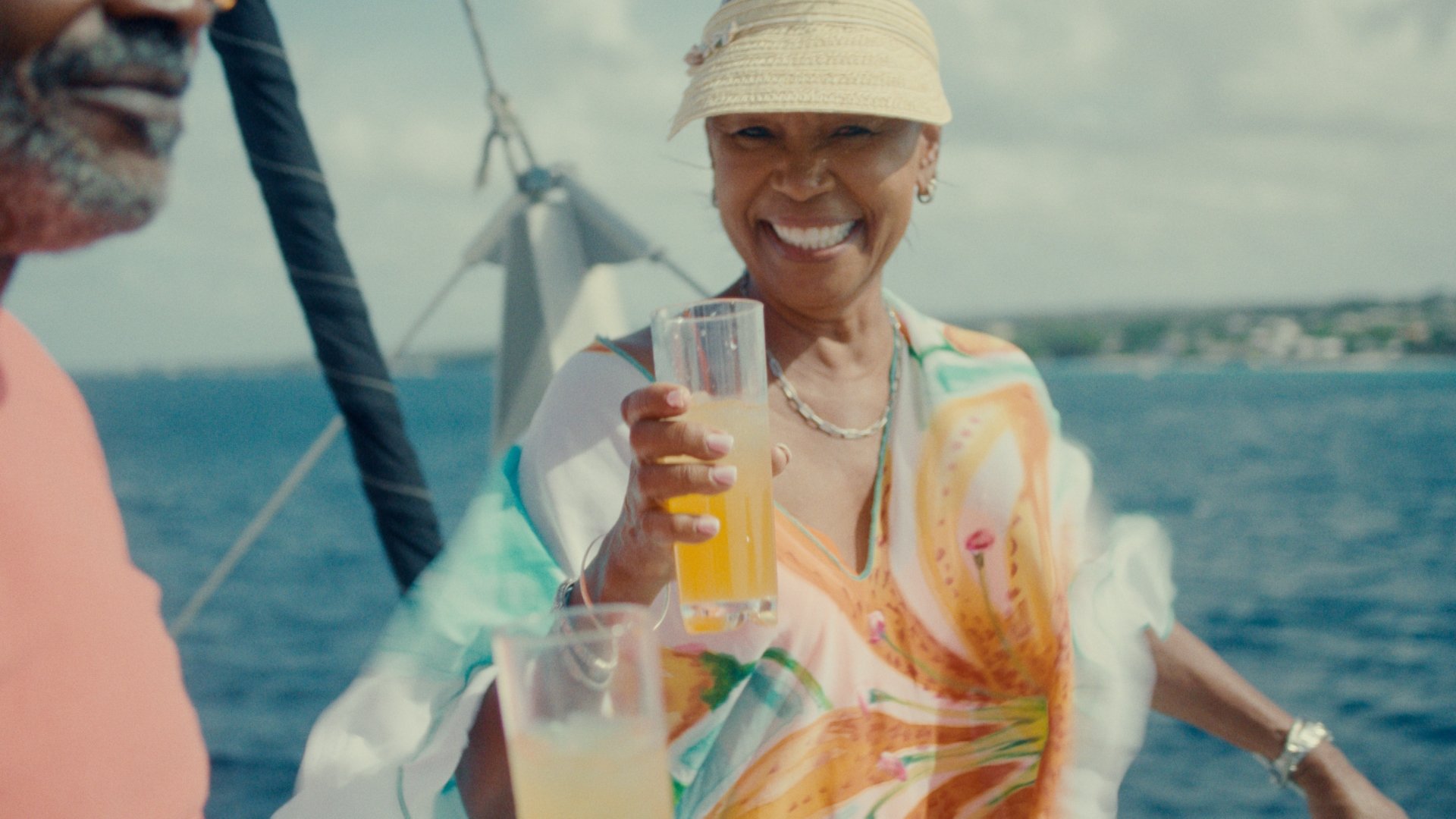 Lady holds up a glass and smiles at the camera.