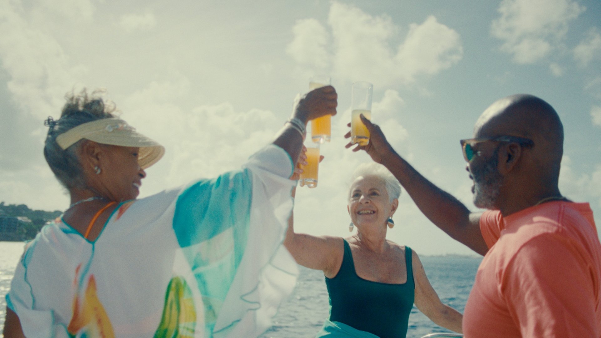 Three friends clink their classes on a boat at sea.