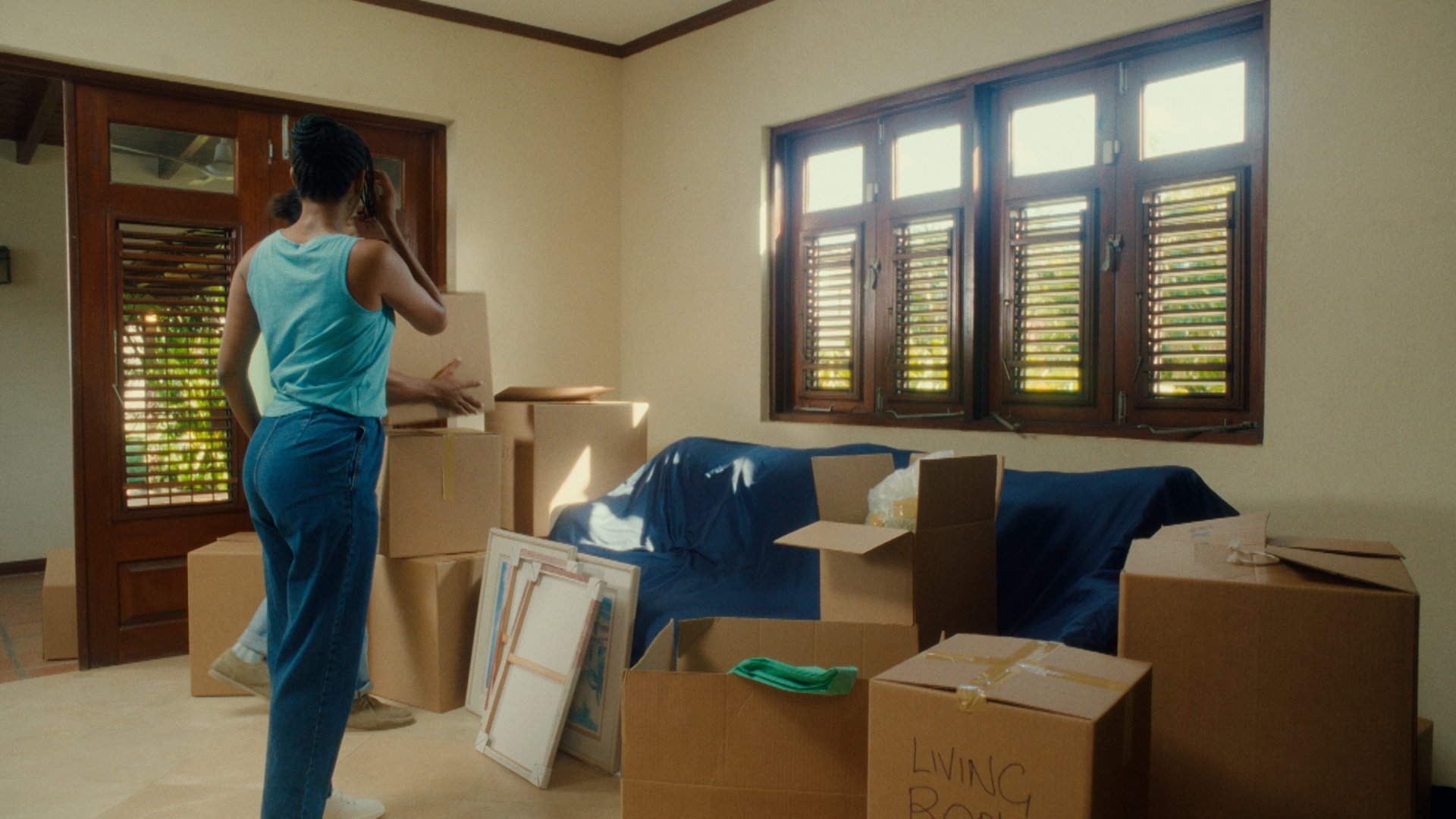A lady stands in front of boxes in her new home.