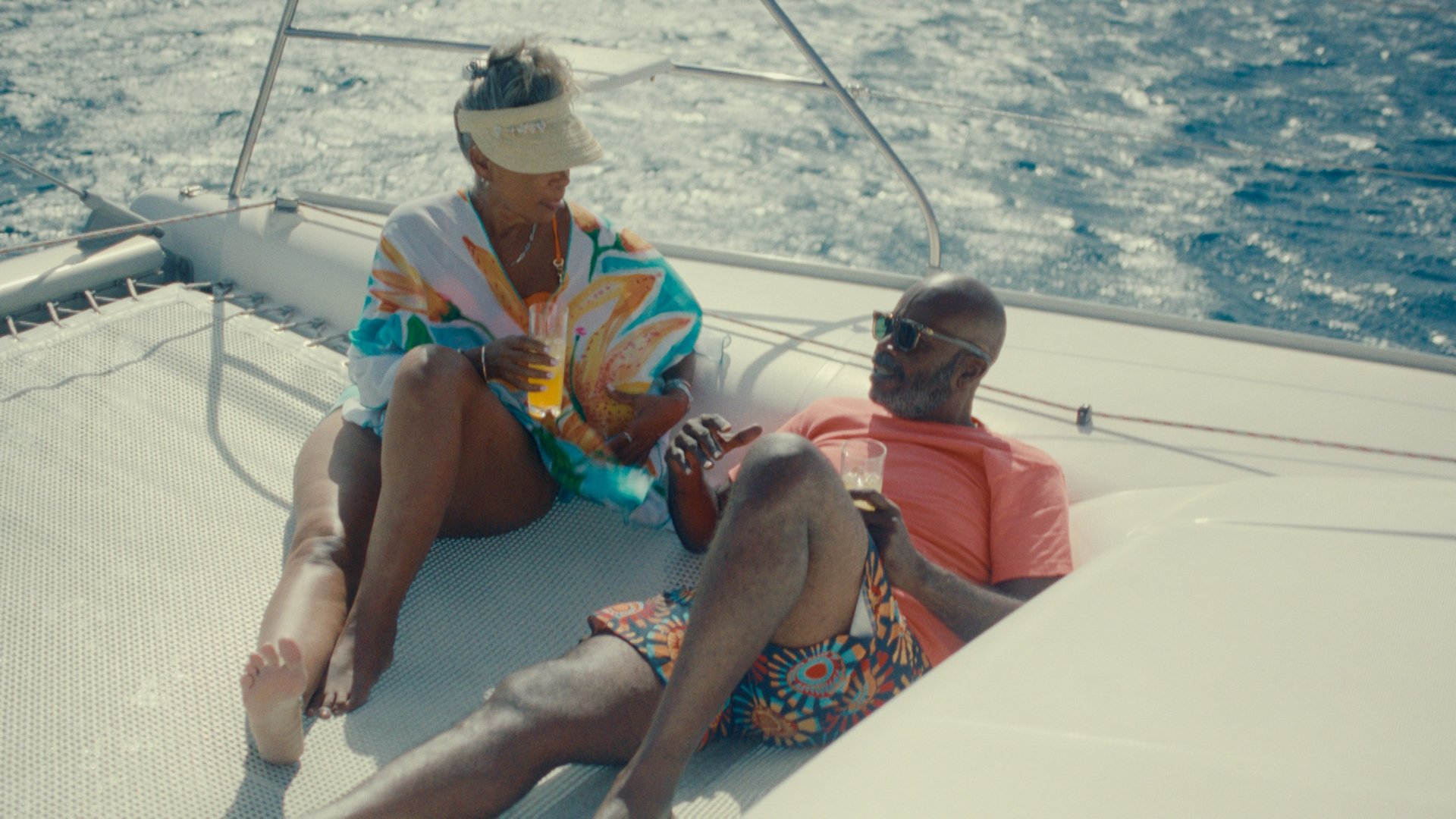 Two people lounge on a boat at sea.