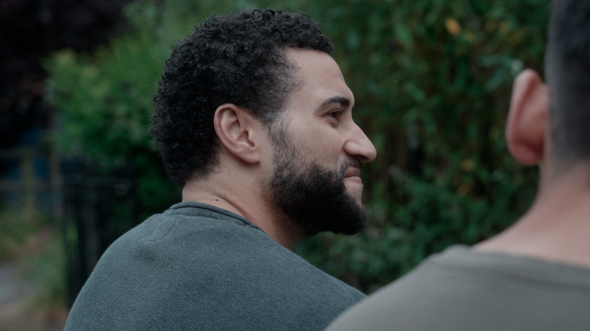 Closeup of a man smiling next to greenery.