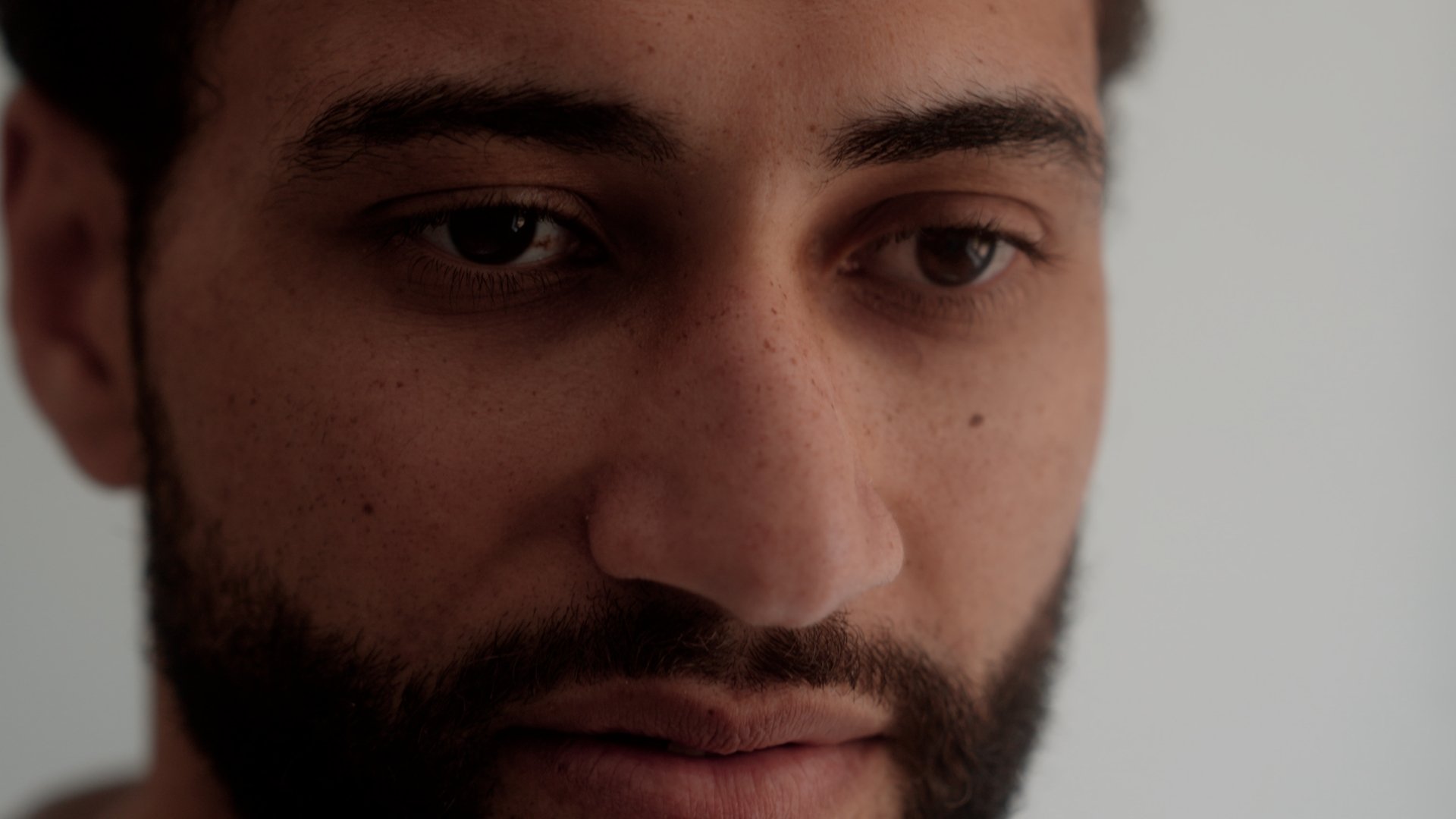 Closeup of a man against a white wall, with a look of concern.