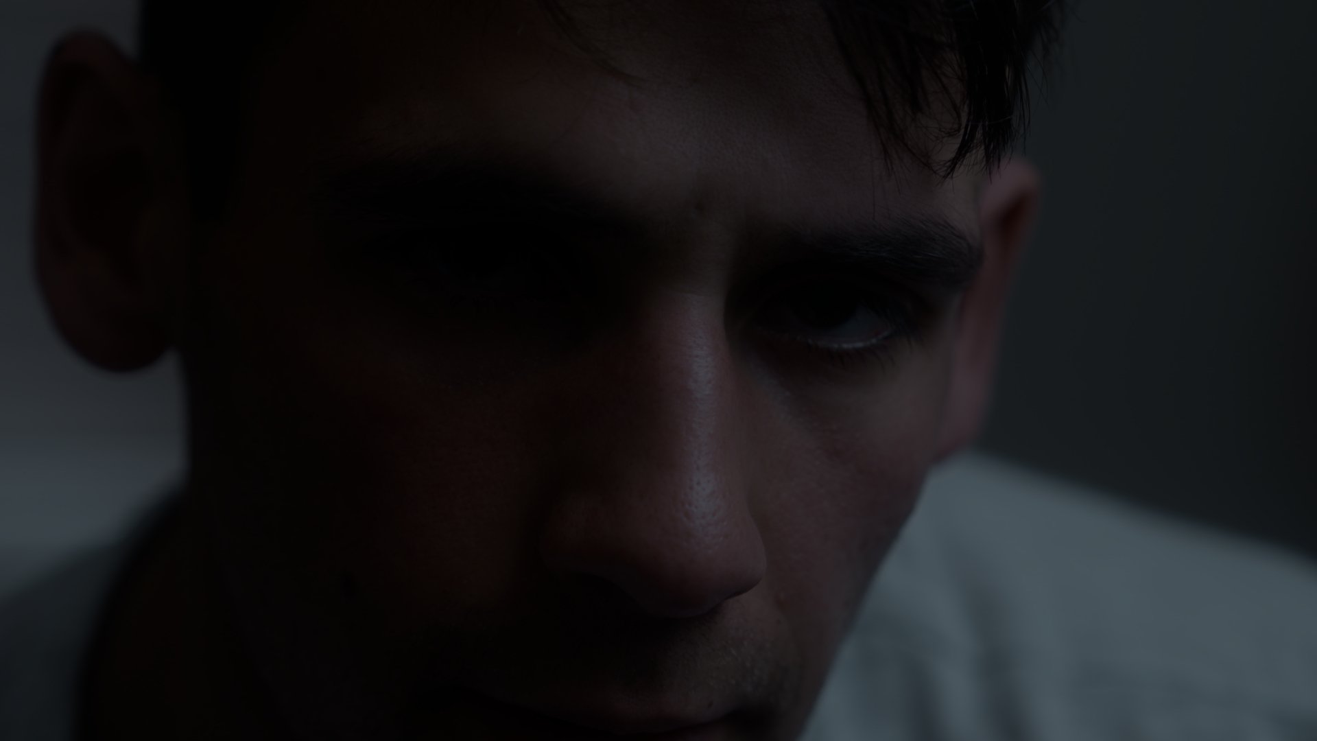 Extreme closeup of a man looking into camera in darkness.