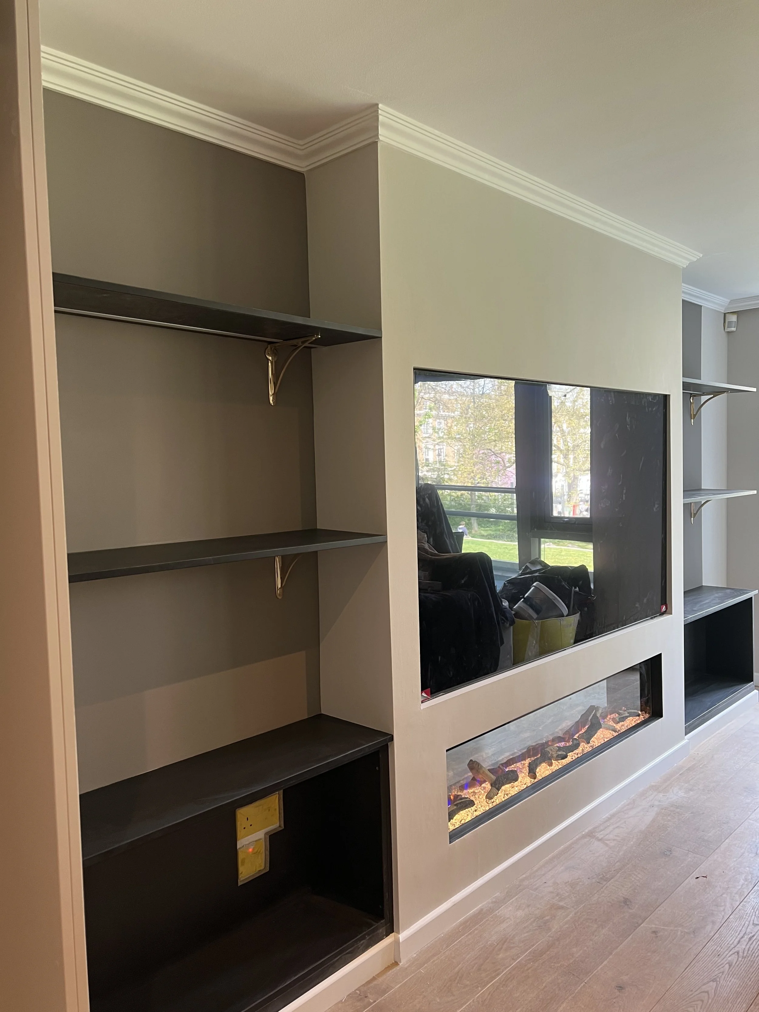Living room built-in entertainment center with shelves on either side and a mounted electric fireplace below a TV in the center.