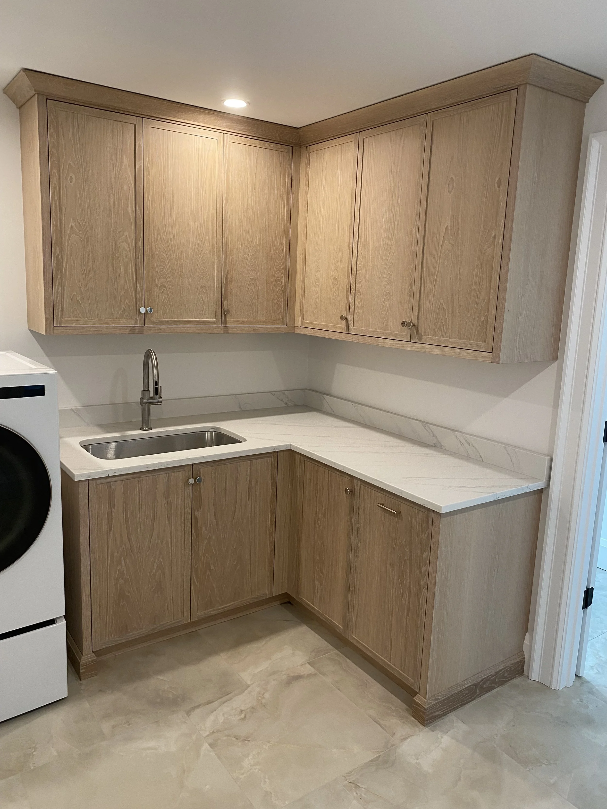 Kitchen with wooden cabinets, marble countertop, and a stainless steel sink.