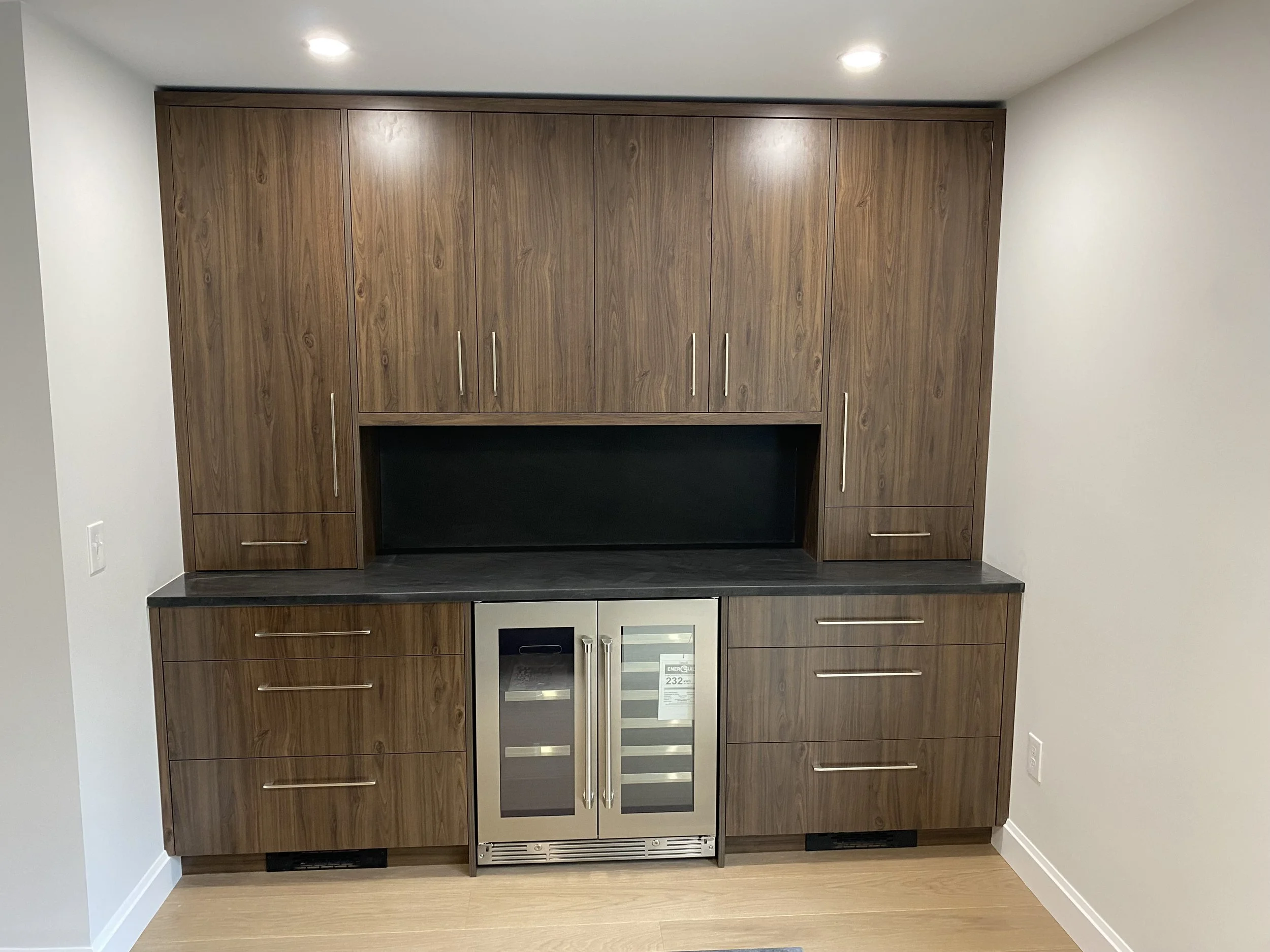 Wooden kitchen cabinetry with a built-in wine cooler and marble countertop.