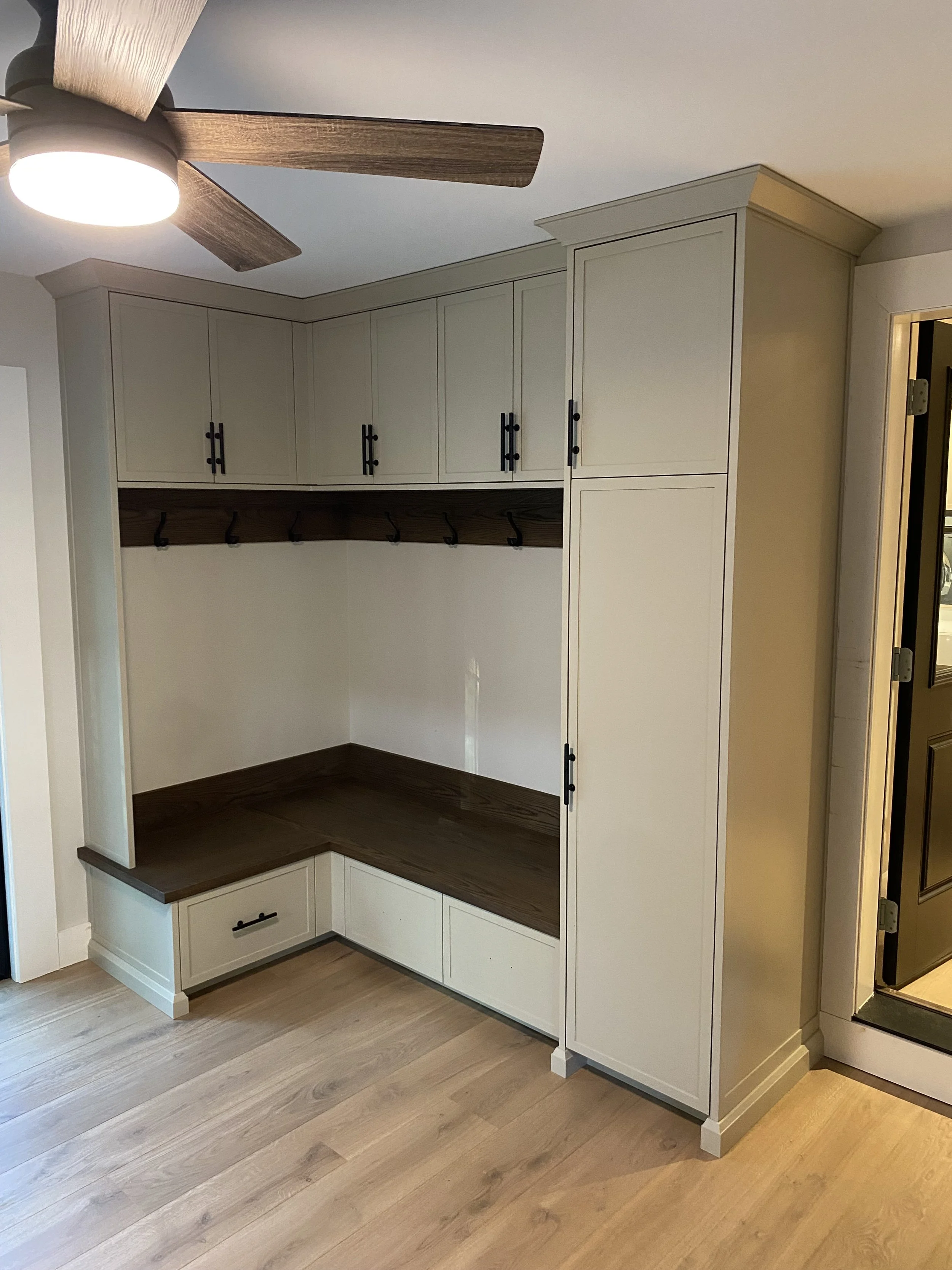 Built-in storage bench with cabinets, hooks, and drawers in a modern home hallway.