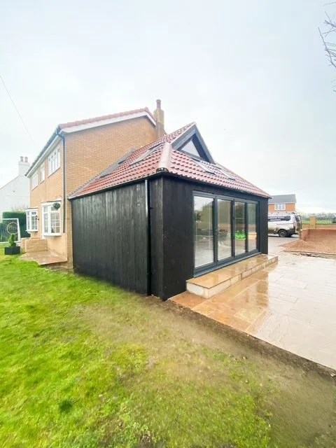 A single - storey burnt larch extension with a Dutch Barn roof and internal remodelling. Kellington East Yorkshire.