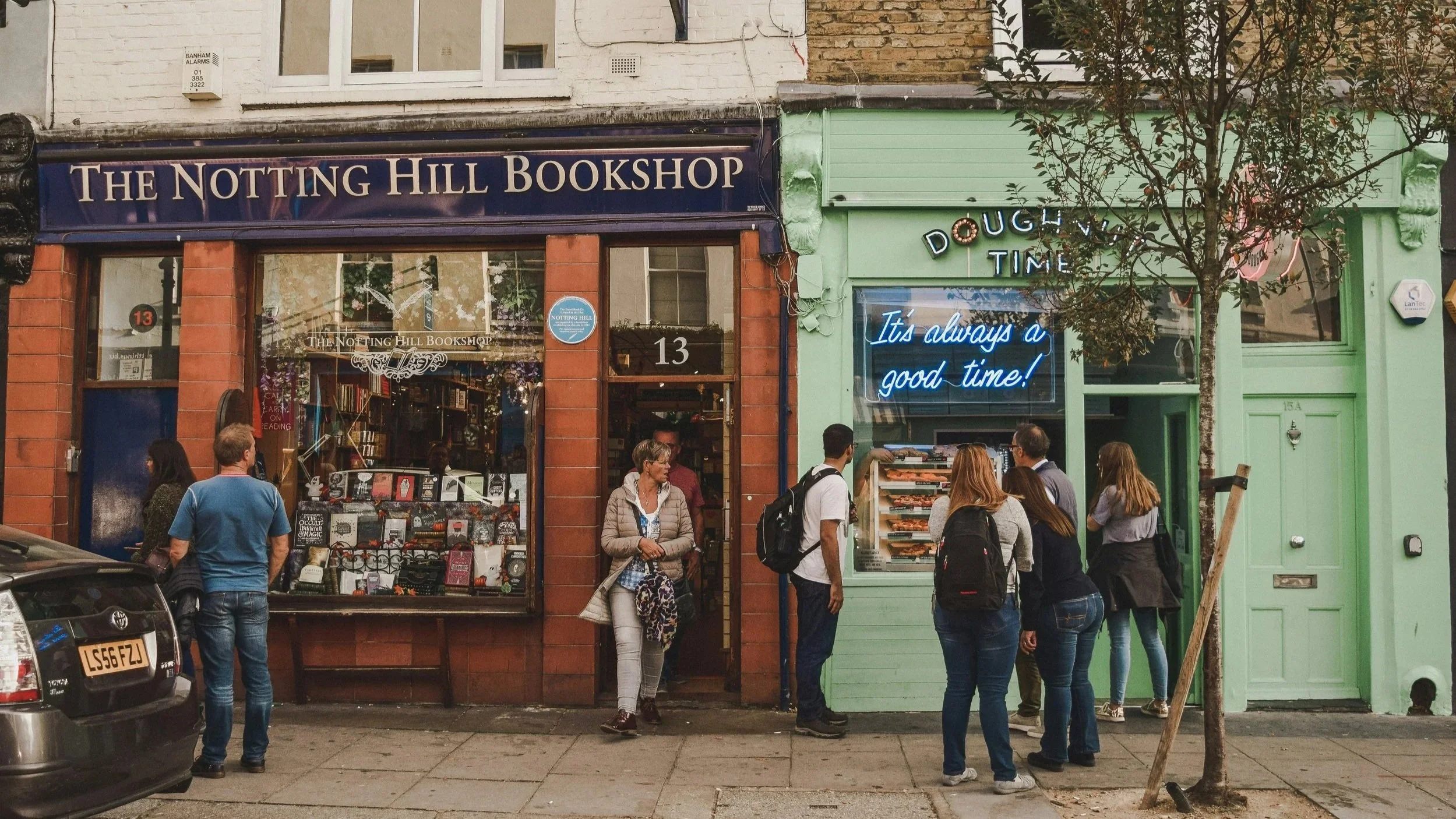 People window shopping in Notting Hill, with a bookshop and doughnut shop in the background