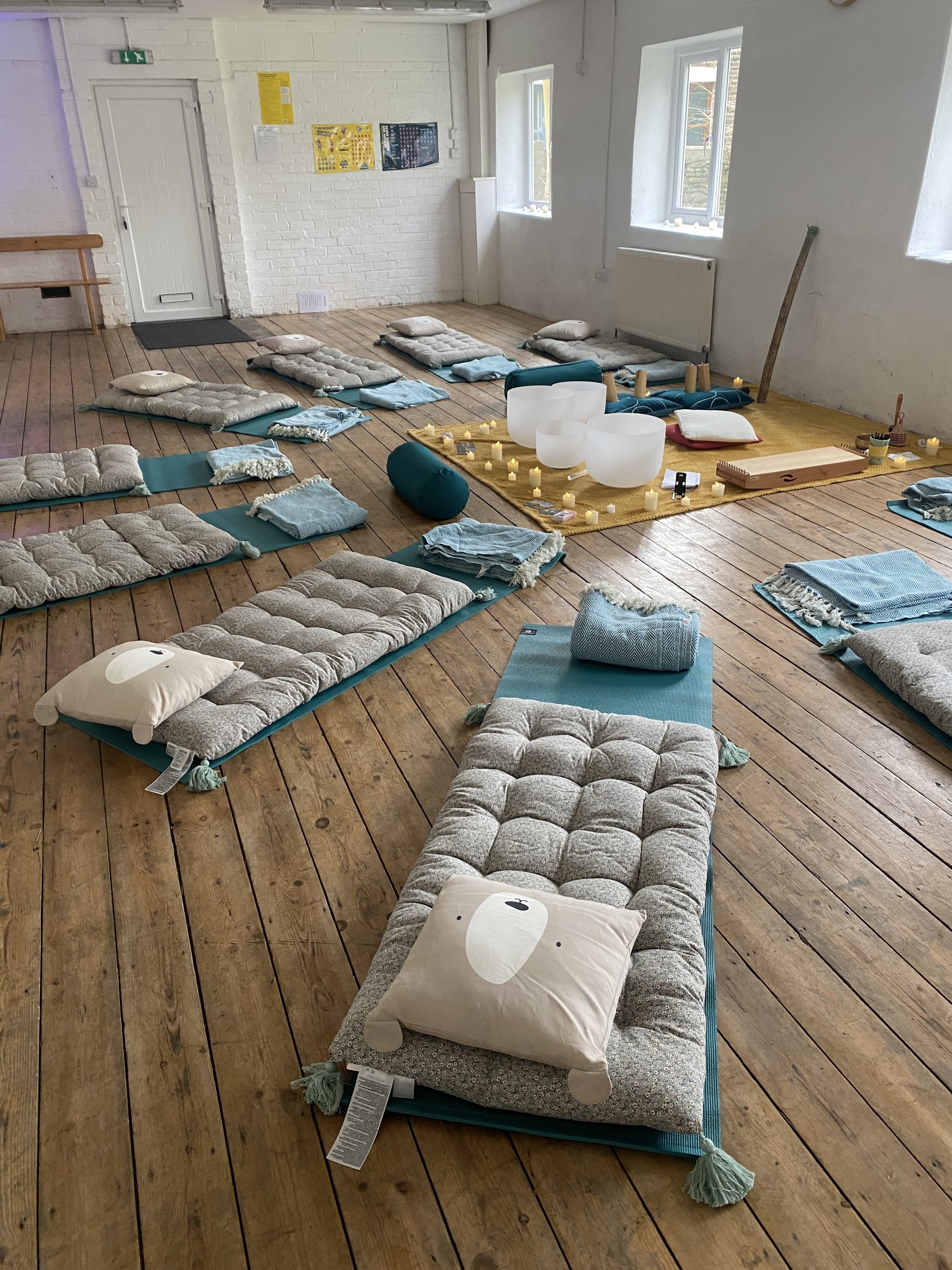 Sound bath therapy space set up with mats, cushions and crystal singing bowls, creating a calm and welcoming environment for meditation and relaxation.