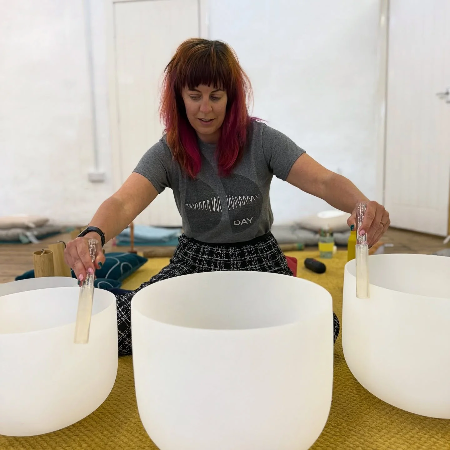 Sound therapist playing crystal singing bowls during a sound bath therapy session, supporting relaxation and stress relief.”