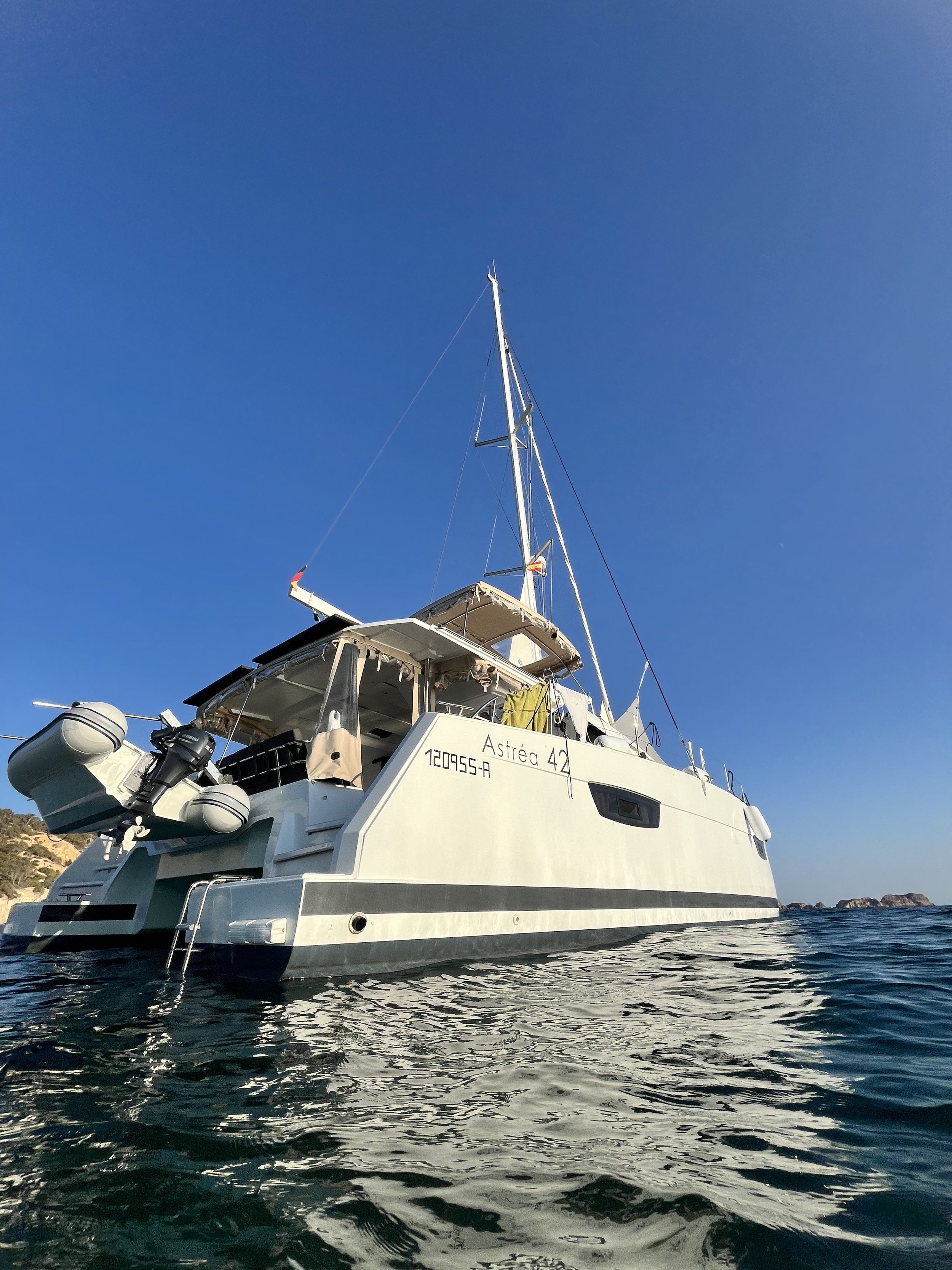 A white sailboat named Astrée 42 floating on blue water with a clear sky in the background.