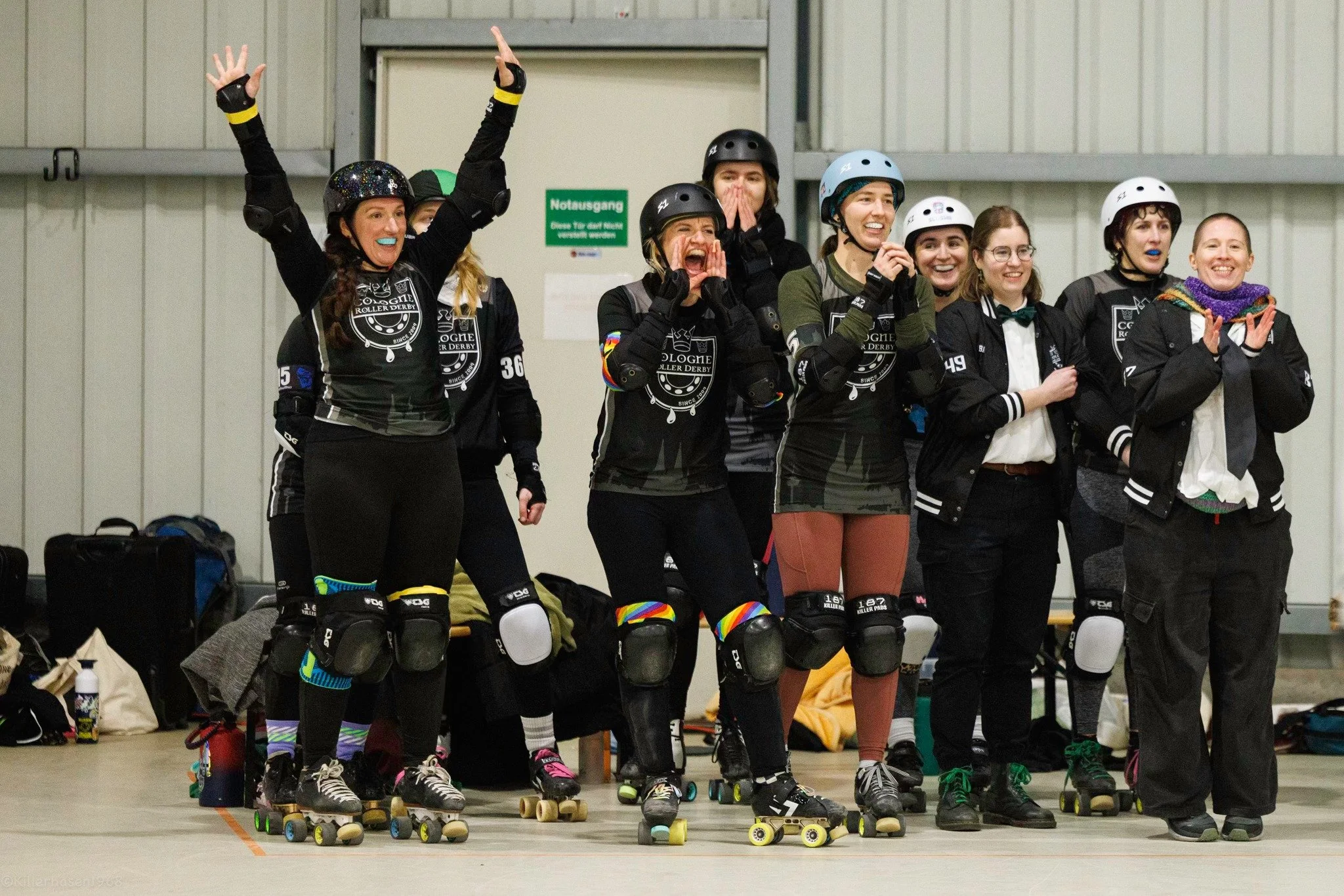 Eine Gruppe von Frauen, die beim Rollerderby spielen, jubeln und lachen.