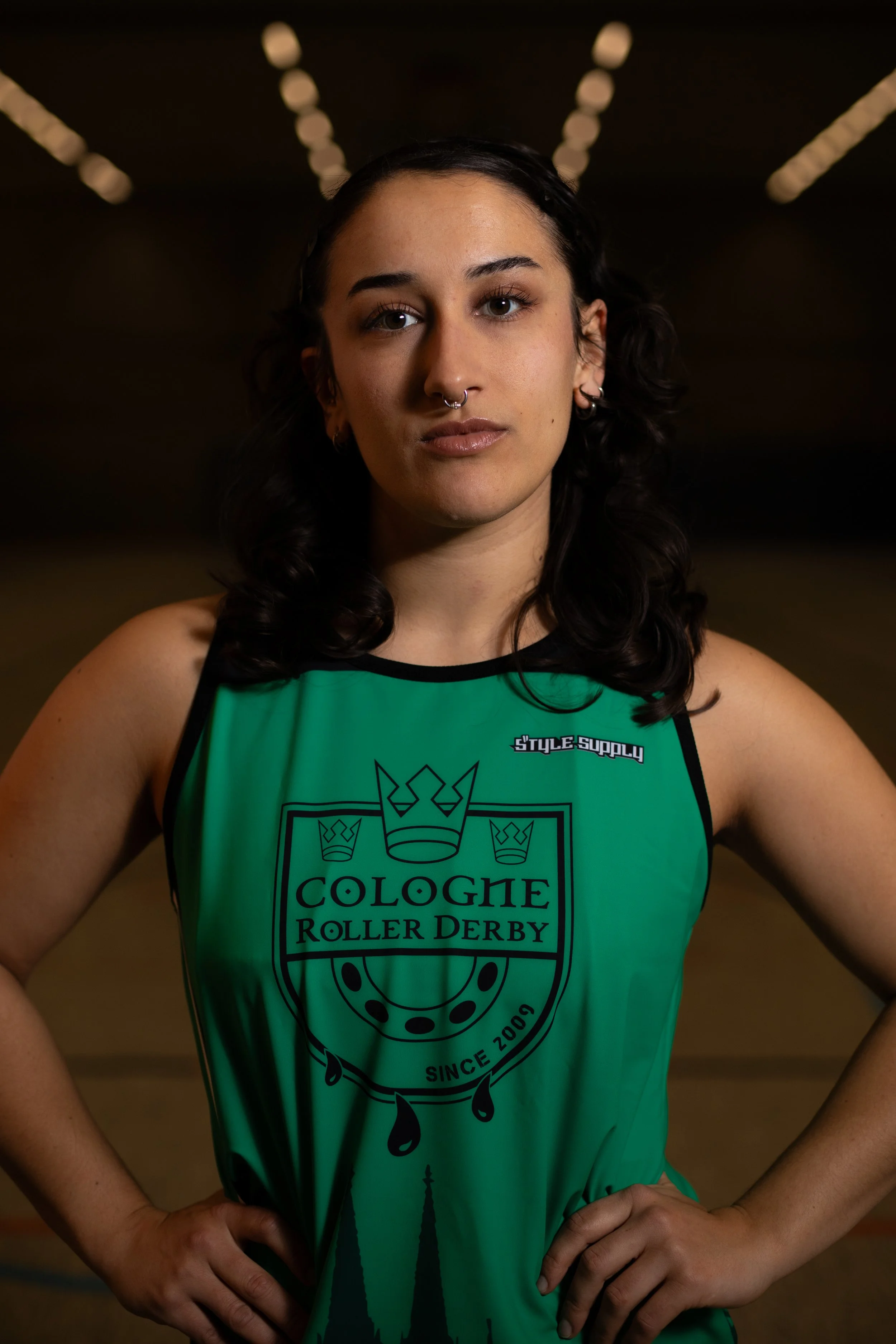 Frau in grüner Roller Derby Mannschaftskleidung in einer Rollschuhhalle.