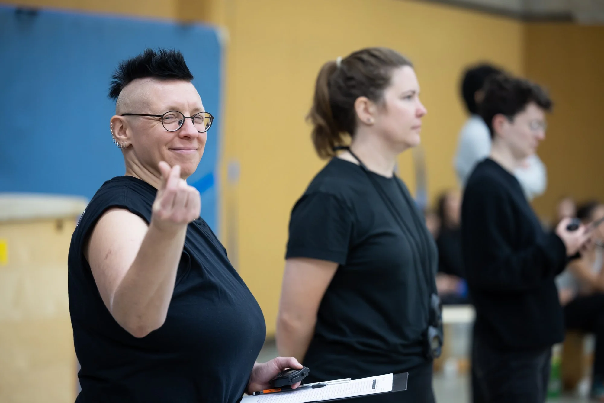 Eine Person macht ein Peace-Zeichen und lächelt in die Kamera, während im Hintergrund weitere Frauen stehen.