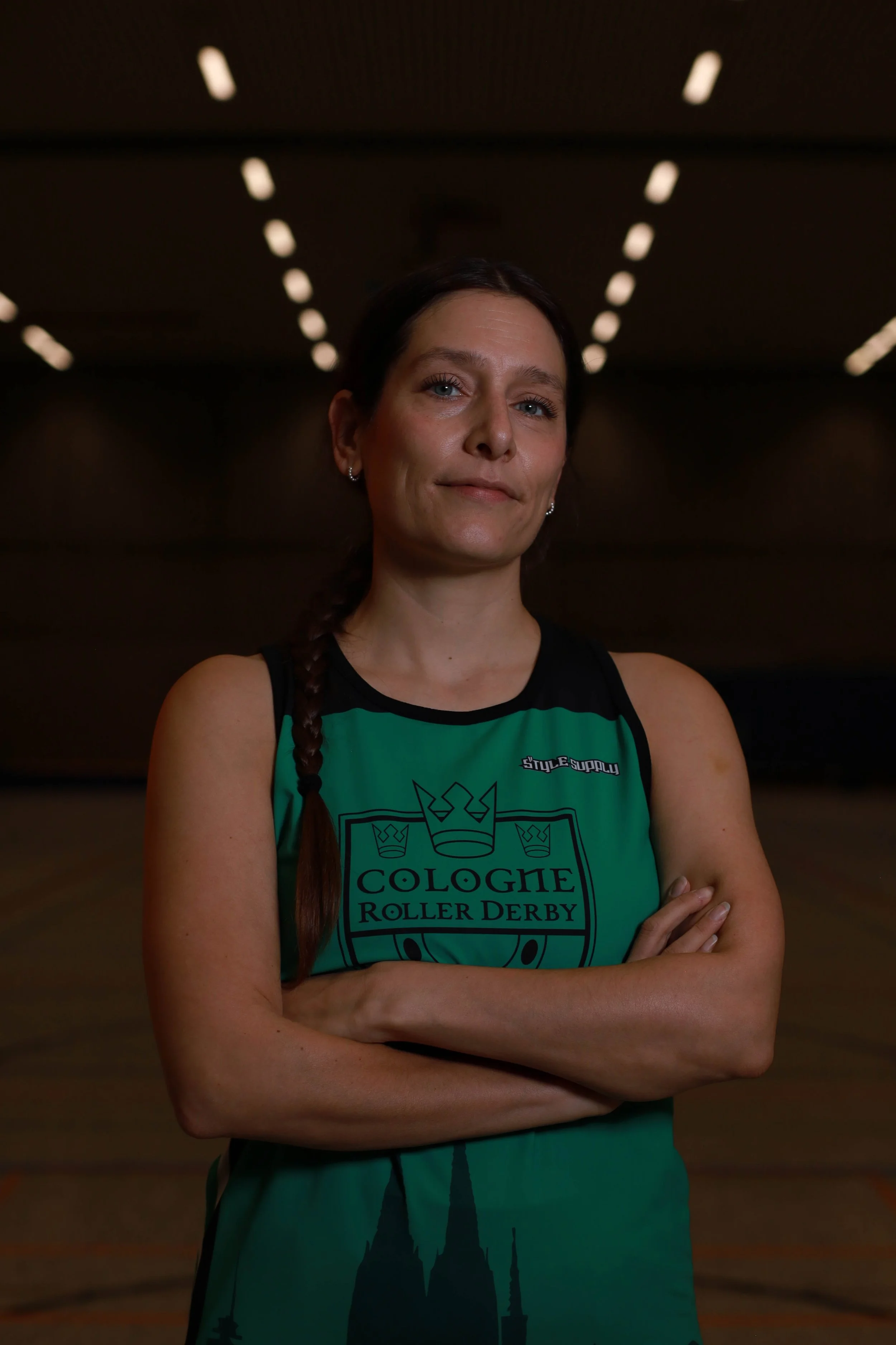Frau in Rollschuh-Trikot mit verschränkten Armen in einer Rollschuhhalle