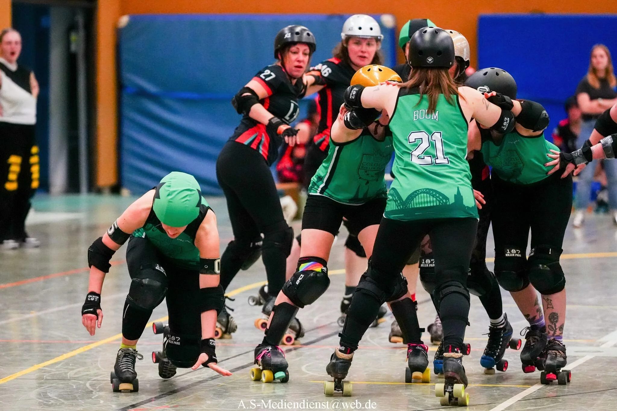 Roller Derby Spiel mit mehreren Spielerinnen in Schutzkleidung in Aktion auf der Indoorrincon.