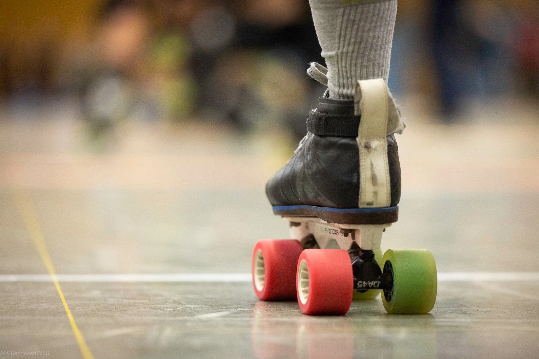 Nahaufnahme eines Rollschuhs auf einer Rollschuhbahn, mit bunten Rollen, auf einem glatten Boden.