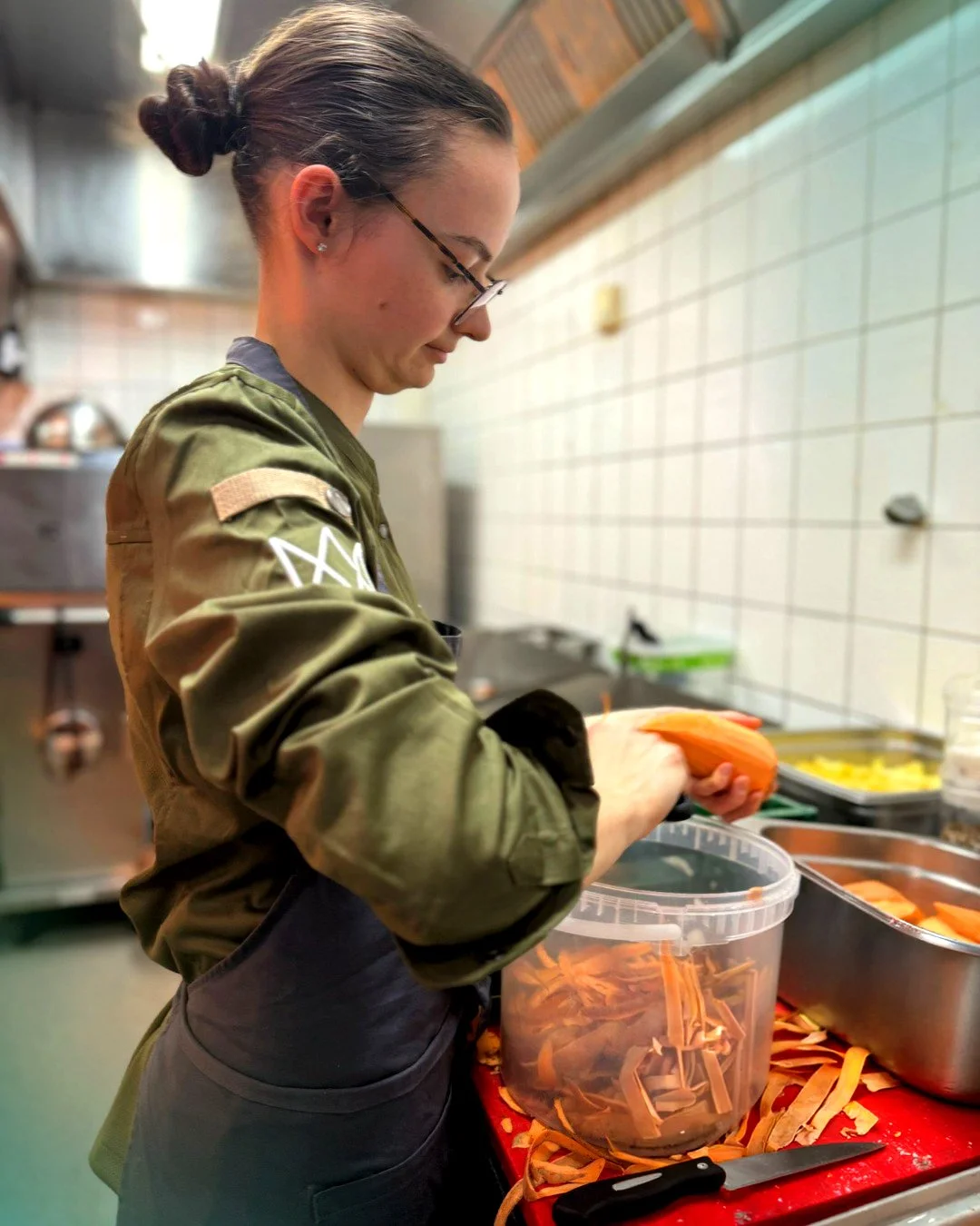  Eine Köchin in der Küche bei der Arbeit, sie schält Karotten. 